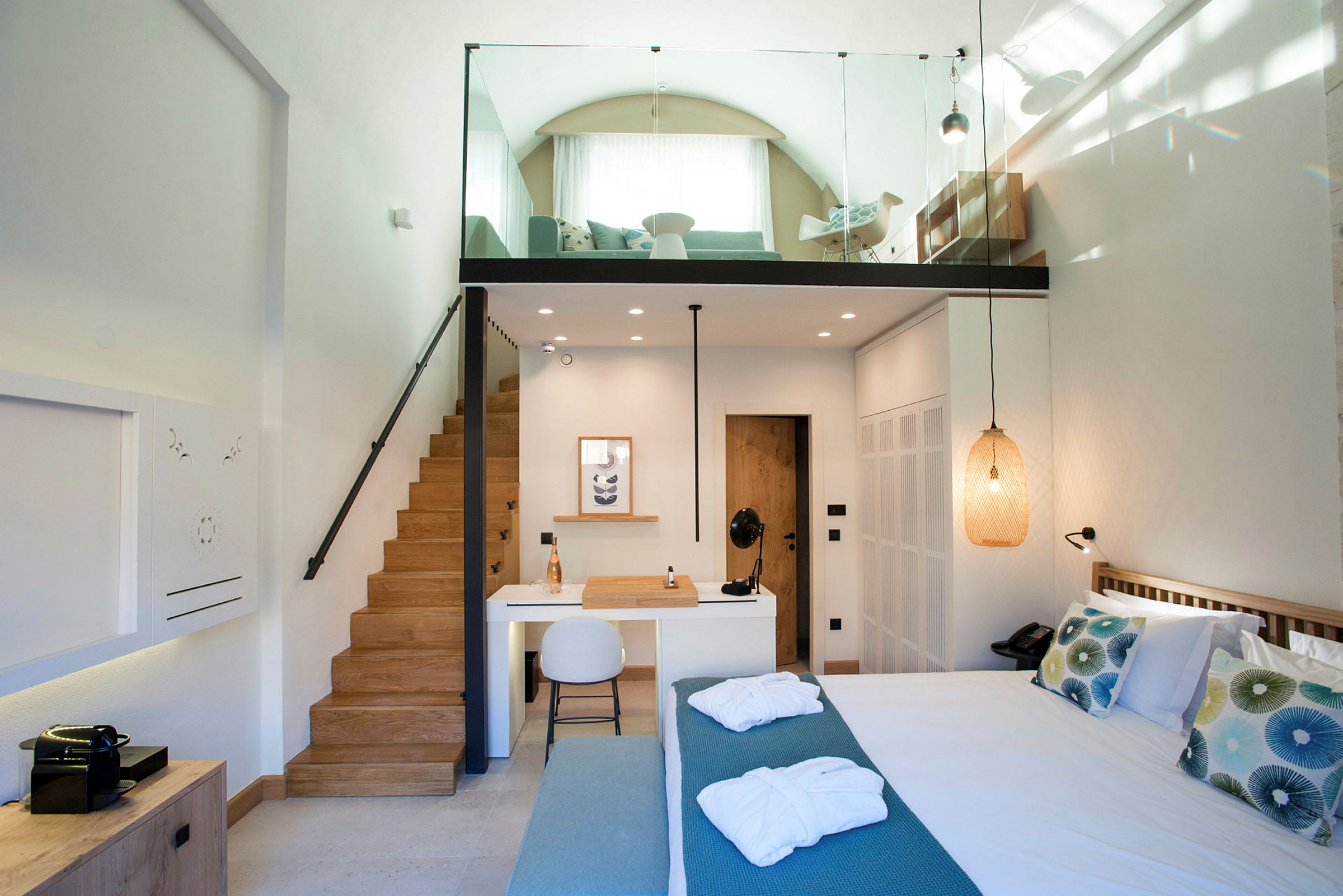 Interiör av ett modernt hotellrum med loft, säng, sittområde och skrivbord. (AI-genererad text)