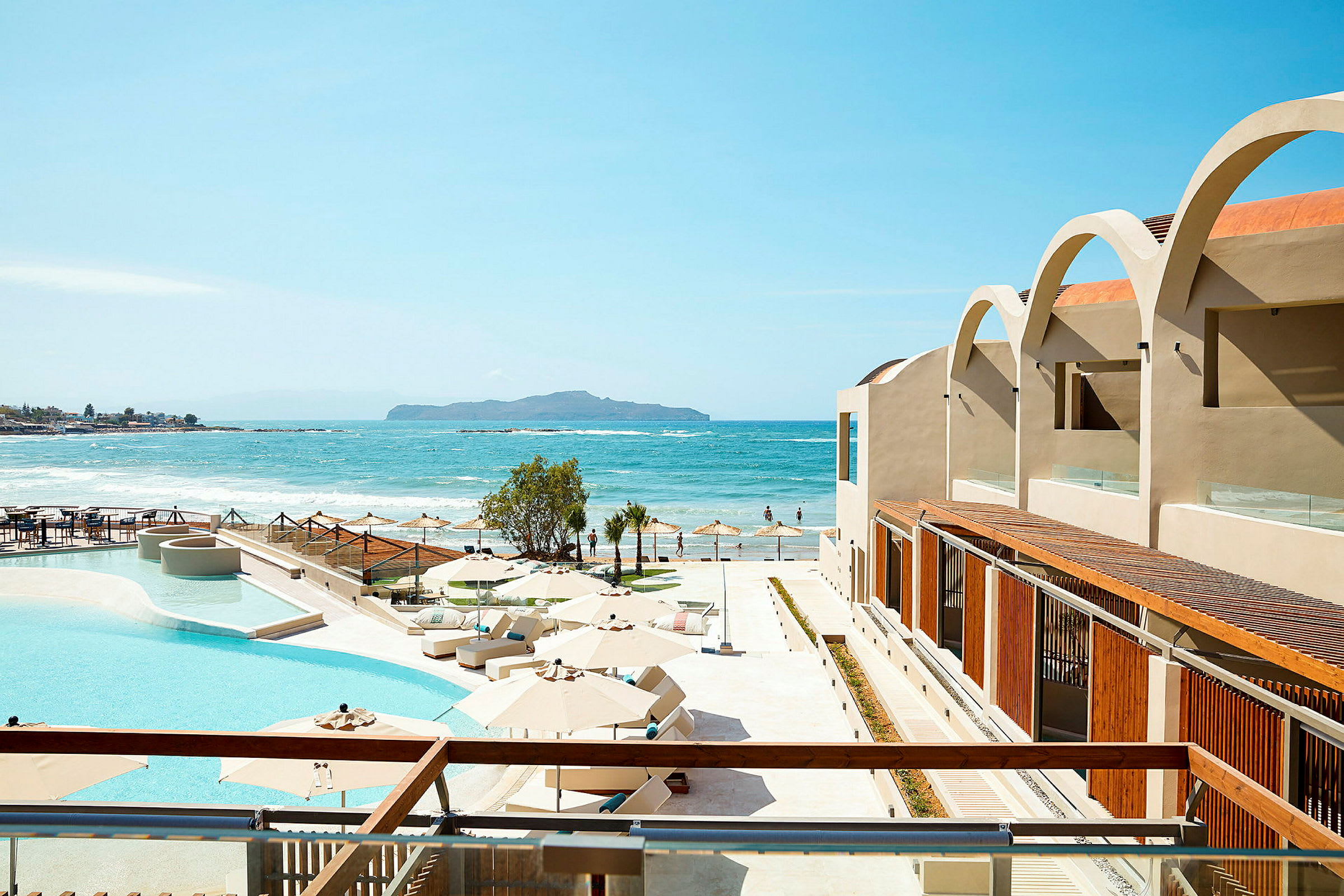 En vy över en hotellpool och terrass med utsikt mot havet. (AI-genererad text)