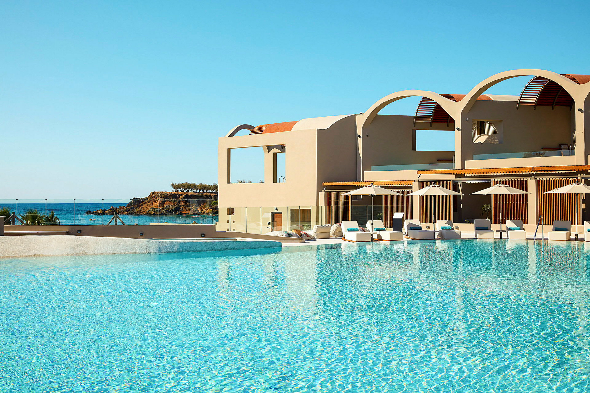 En swimmingpool vid ett hotell med havet i bakgrunden. (AI-genererad text)