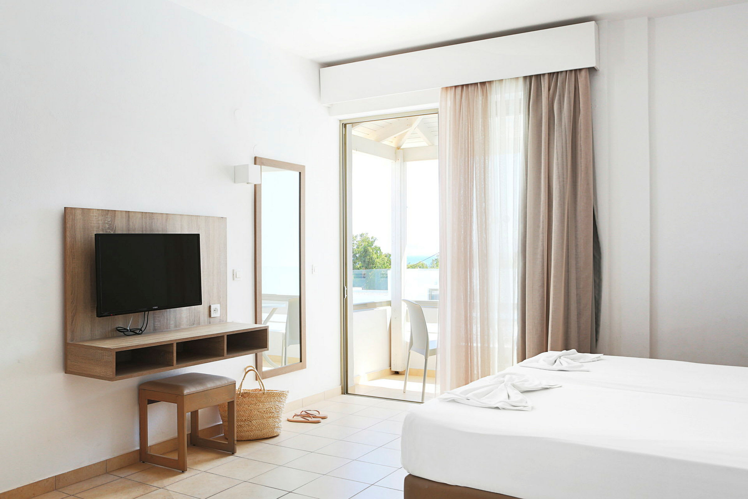 Ett hotellrum med två sängar, en TV, en spegel och en balkong. (AI-genererad text)