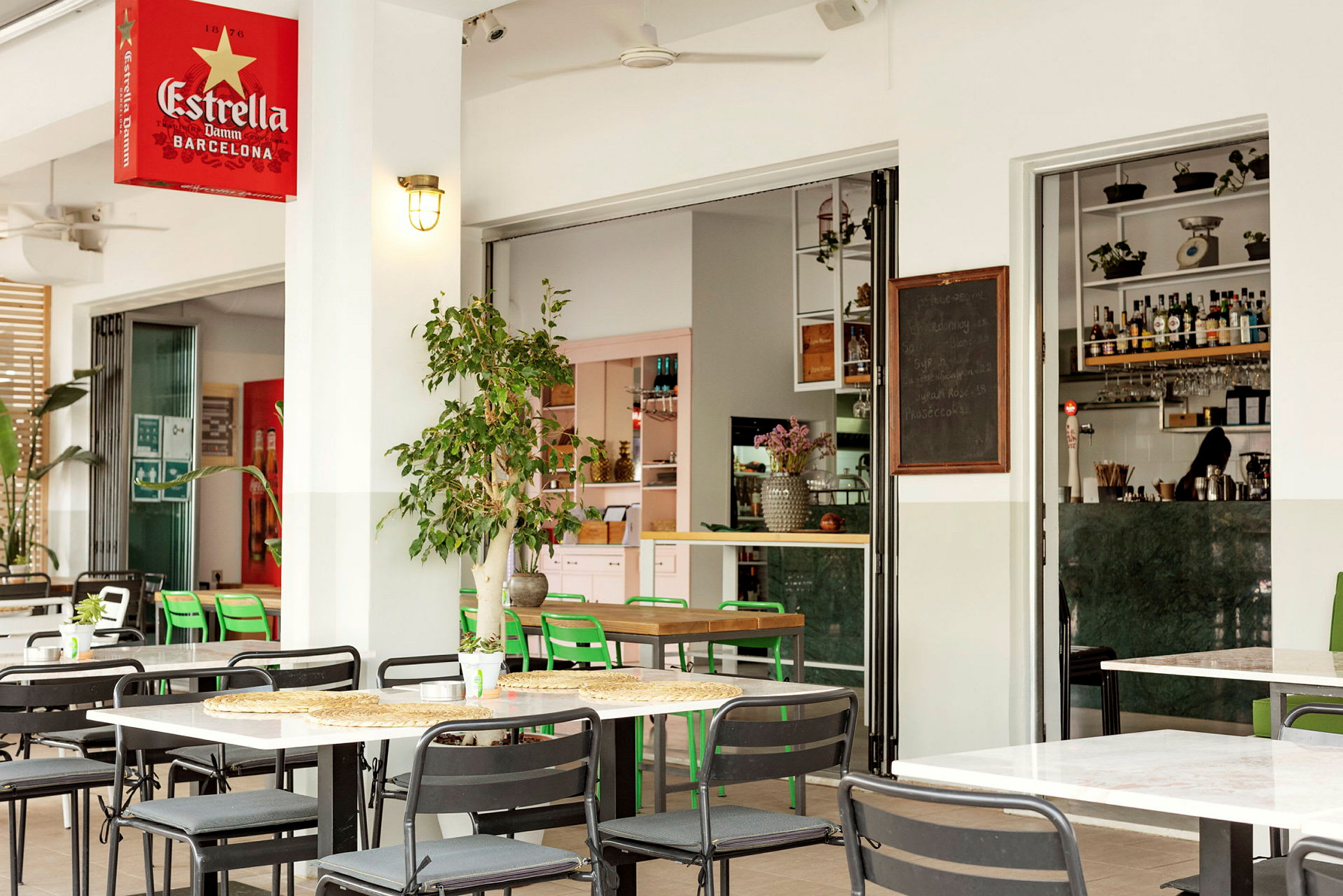 Uteservering med matbord och stolar, med en öppen ingång till en modern bar. (AI-genererad text)