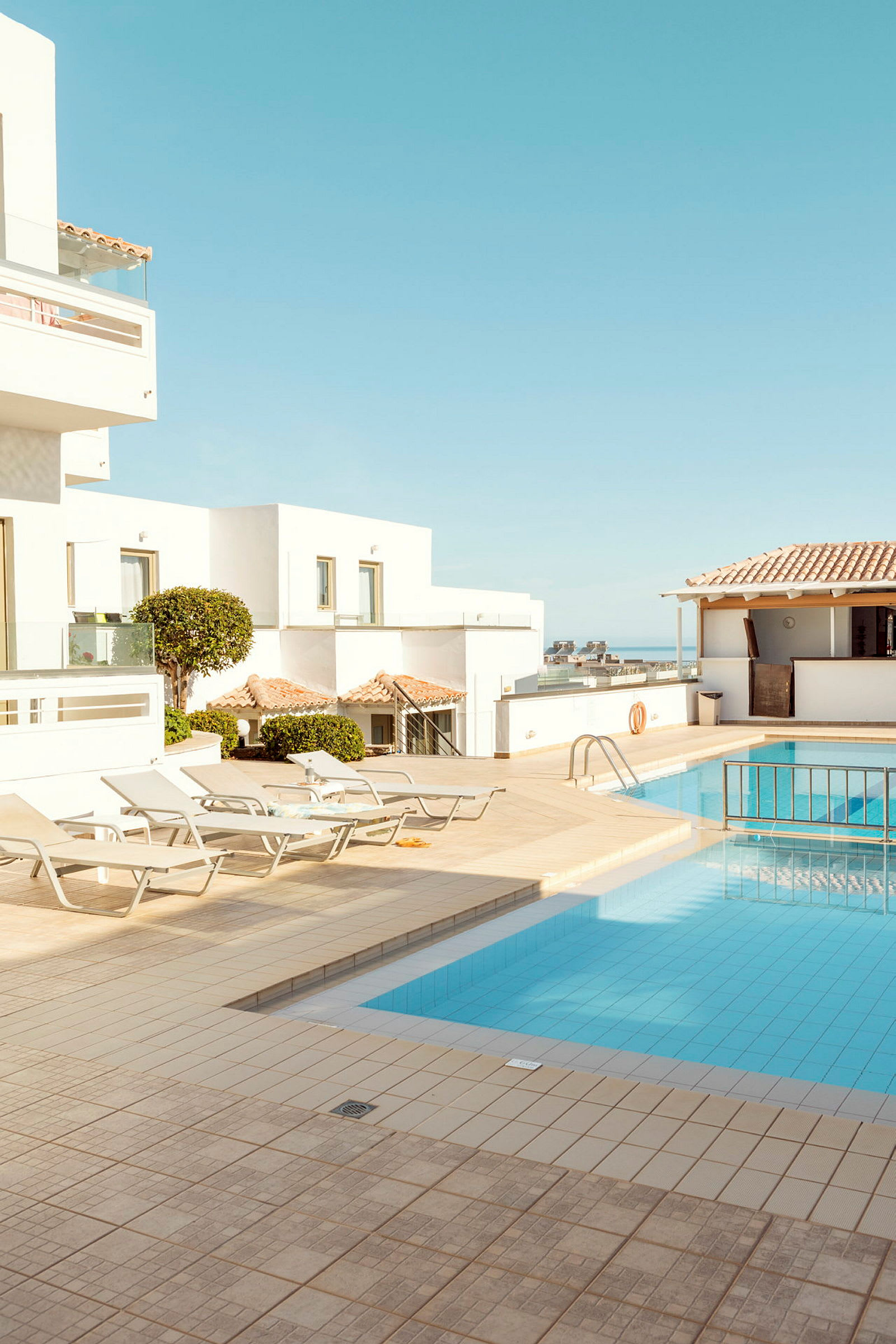 Bild av en hotellpoolområde med solstolar och byggnader i bakgrunden. (AI-genererad text)