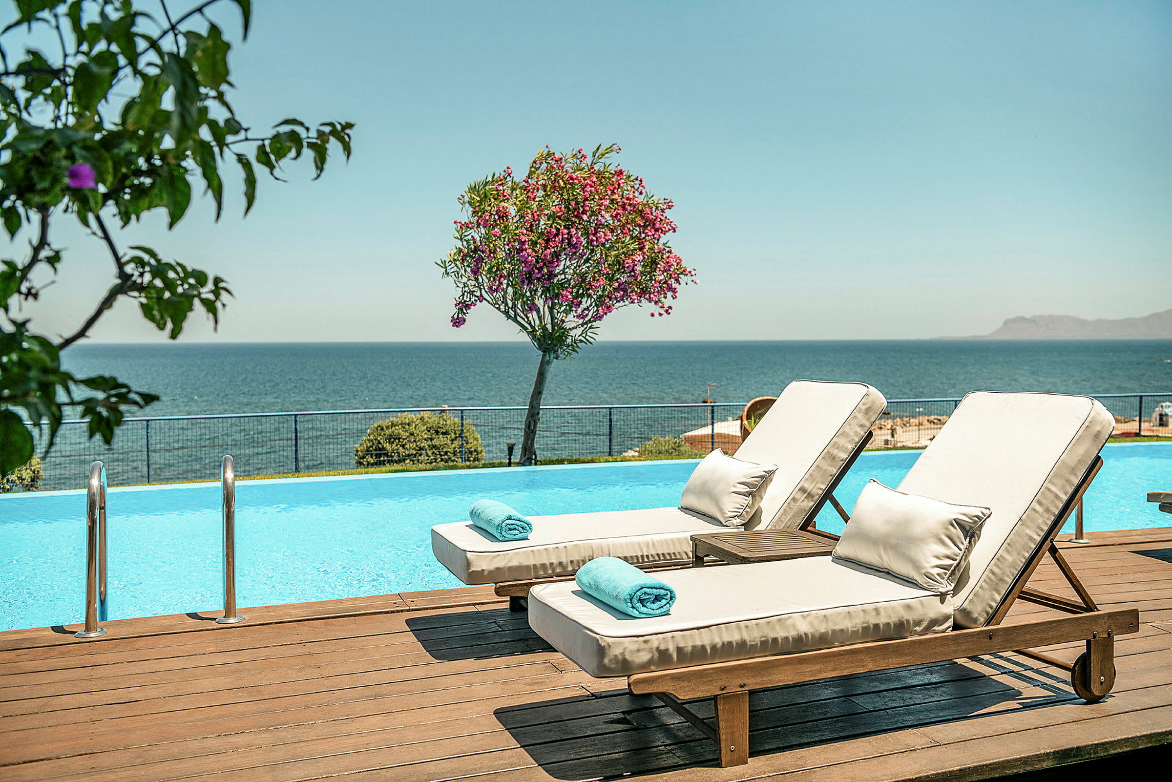Två solstolar vid en pool med utsikt över havet. (AI-genererad text)
