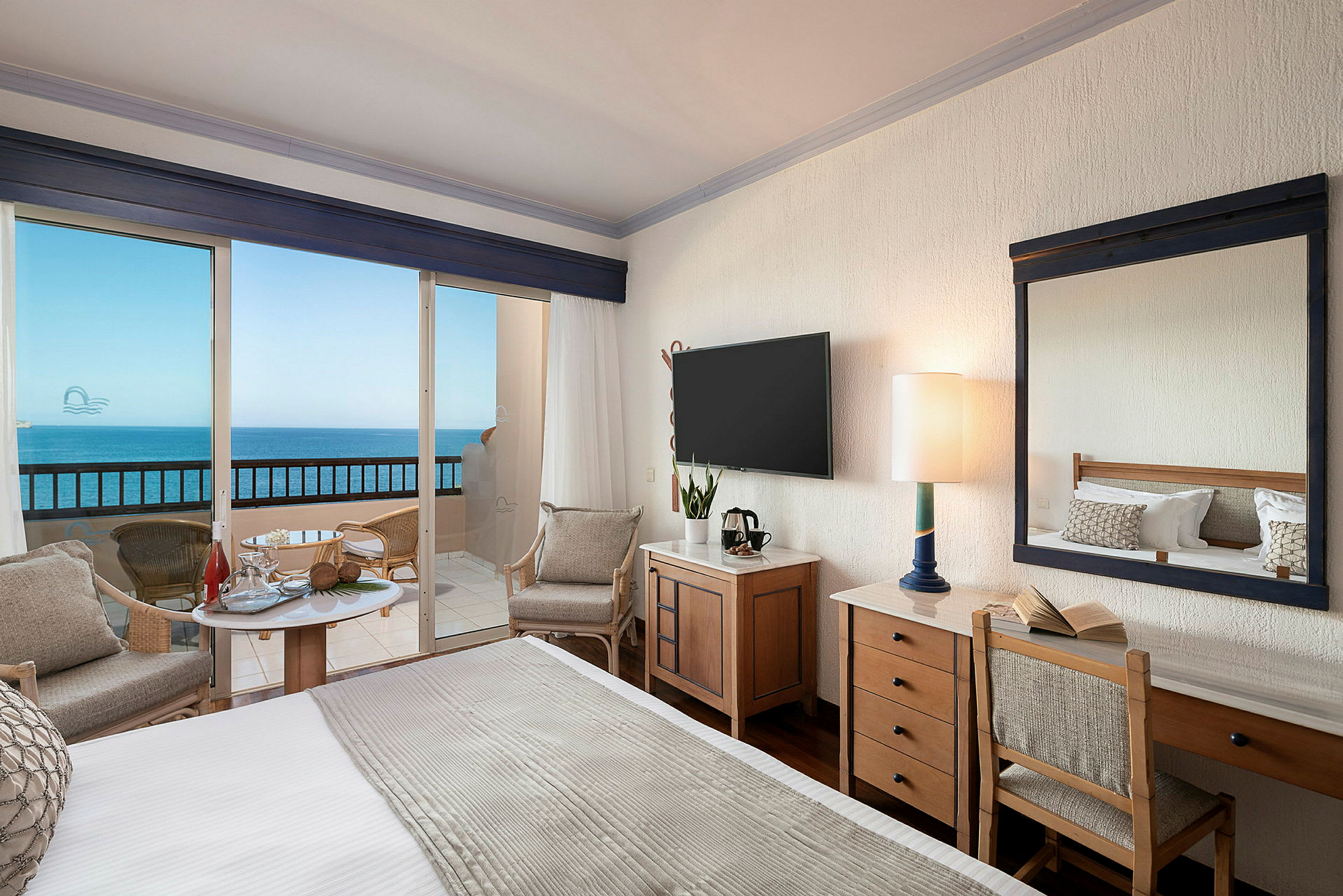 Hotellrum med havsutsikt genom fönster och balkong. (AI-genererad text)