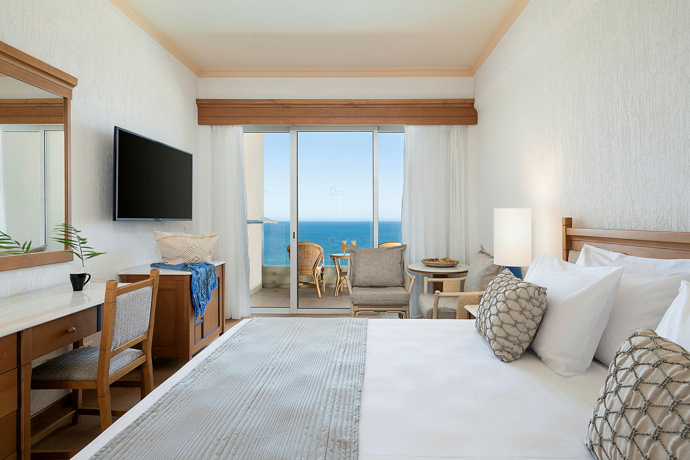 Hotellrum med utsikt mot havet genom stora glasdörrar. (AI-genererad text)