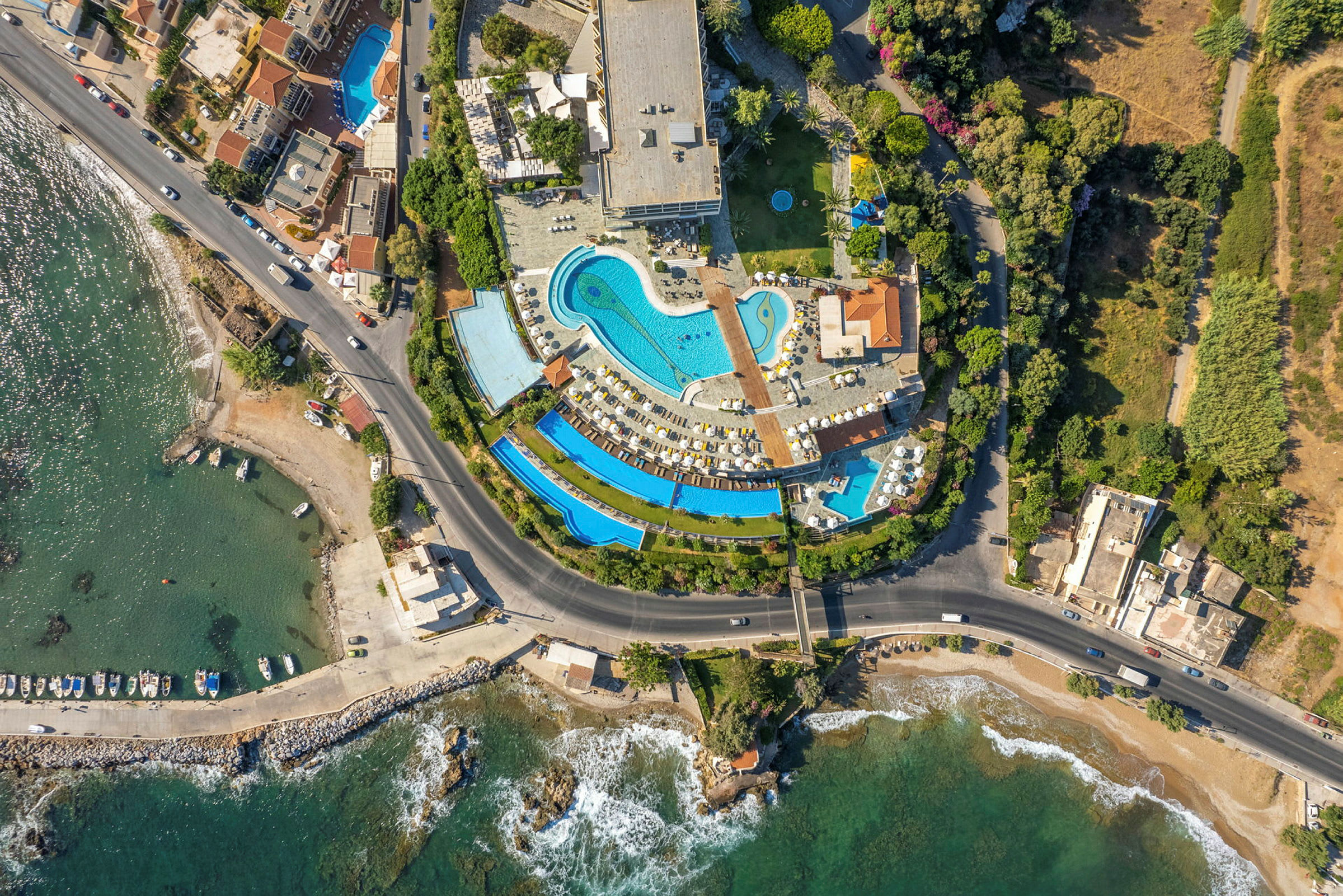 Flygbild över hotellområde med pooler bredvid havet. (AI-genererad text)