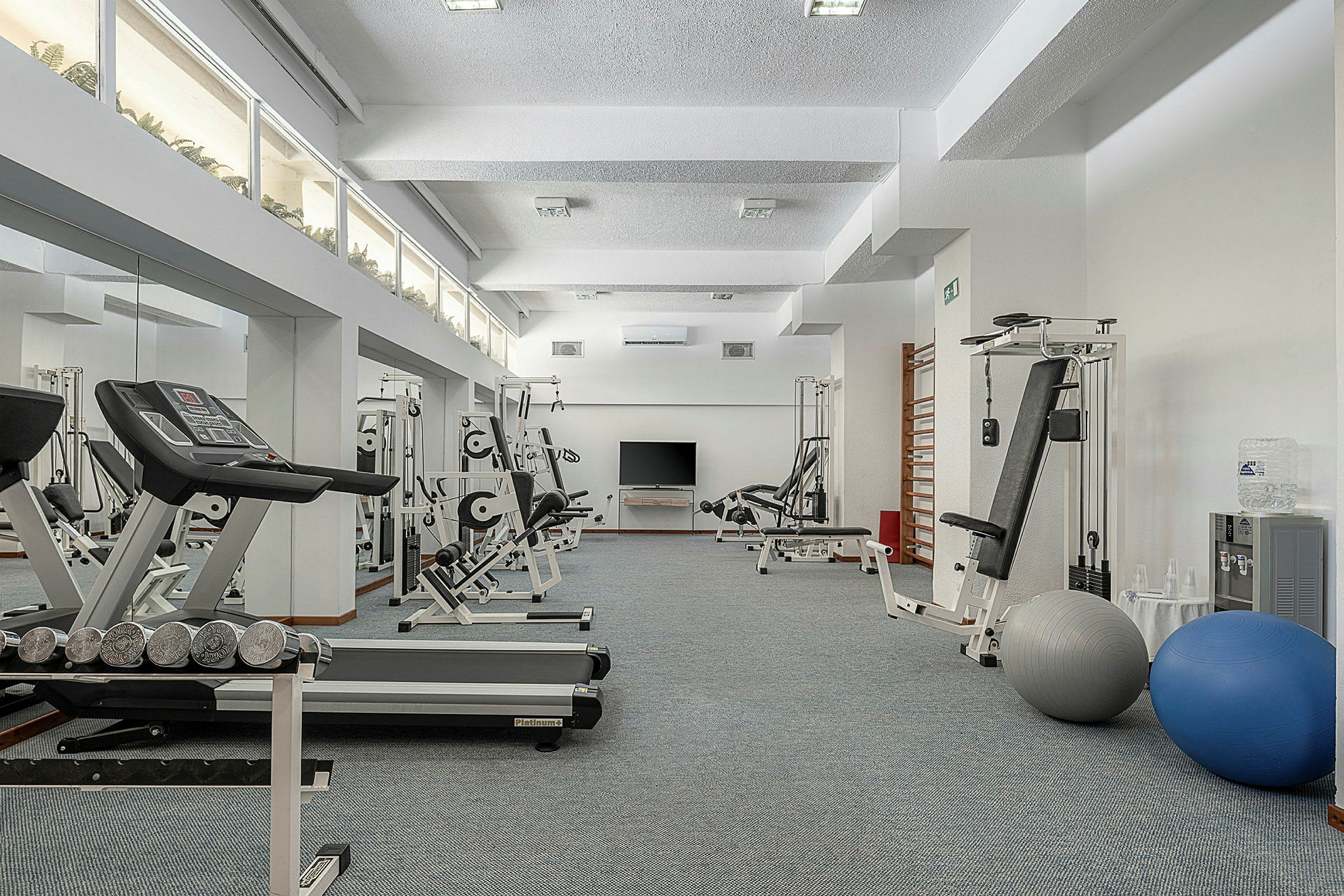 Bild av ett gym med olika träningsredskap som löpband och styrketräningsmaskiner. (AI-genererad text)