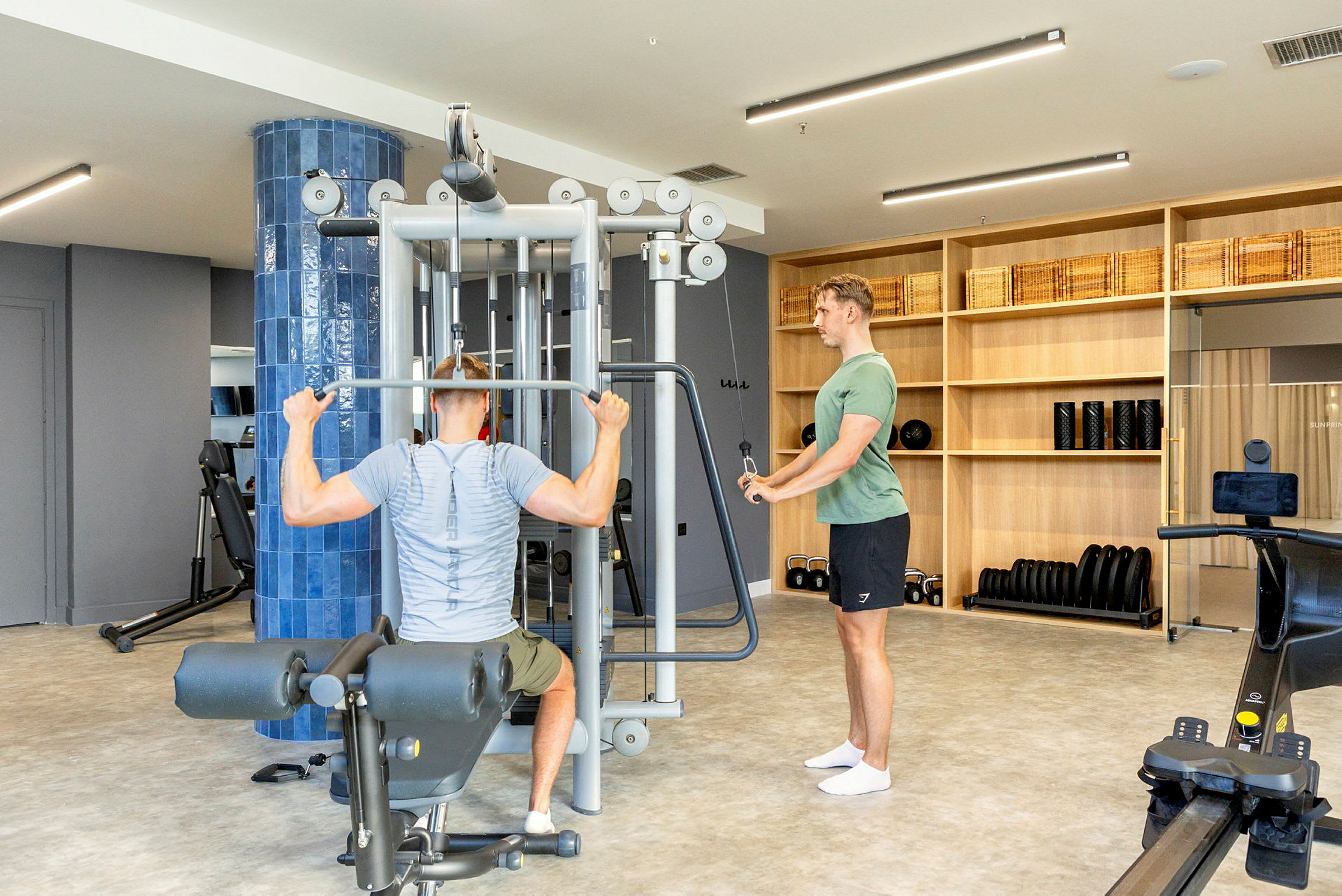 Träningsutrustning i gym med personer som använder en träningsmaskin. (AI-genererad text)