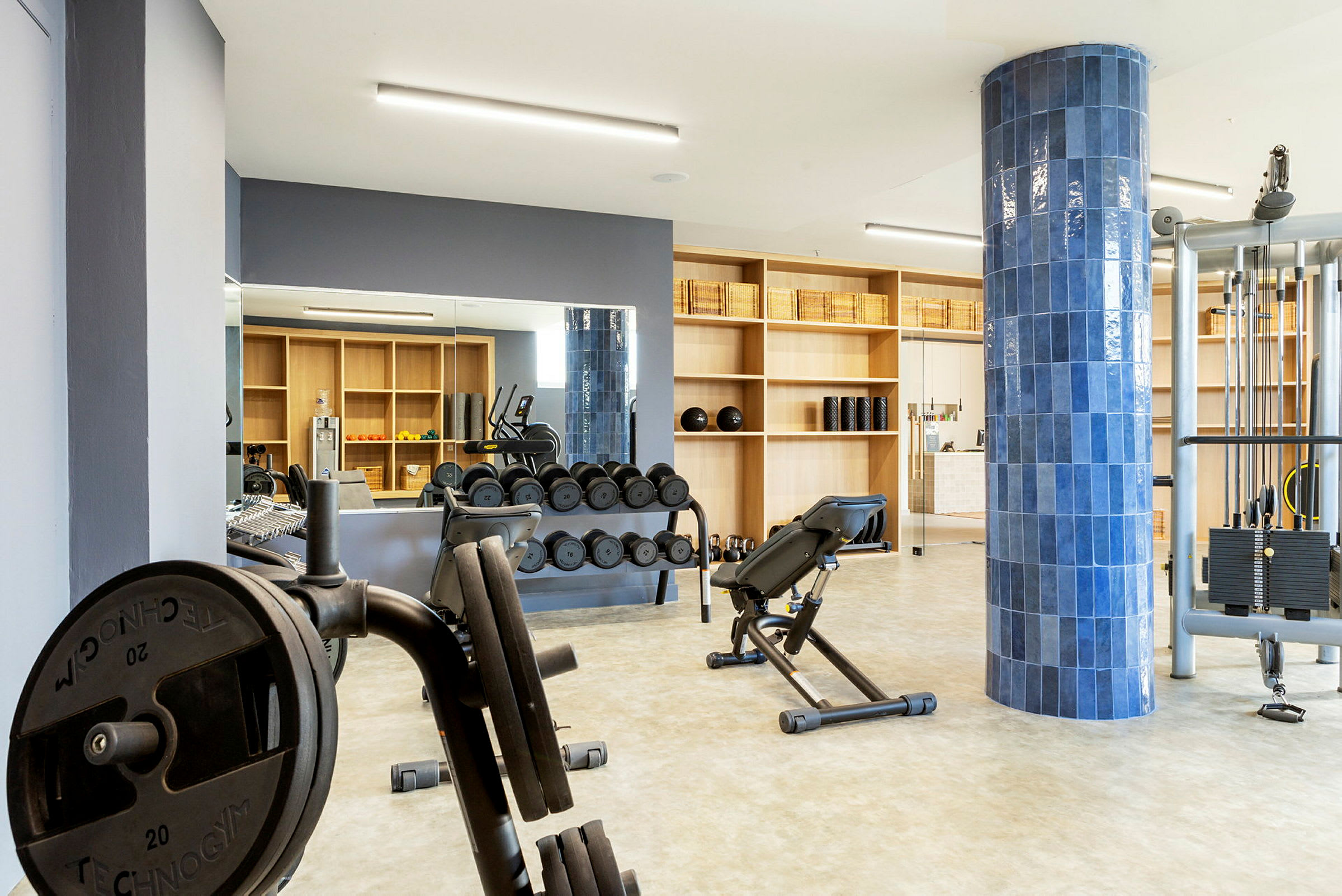 Ett gym med träningsutrustning, inklusive vikter, träningsbänk och maskiner. (AI-genererad text)