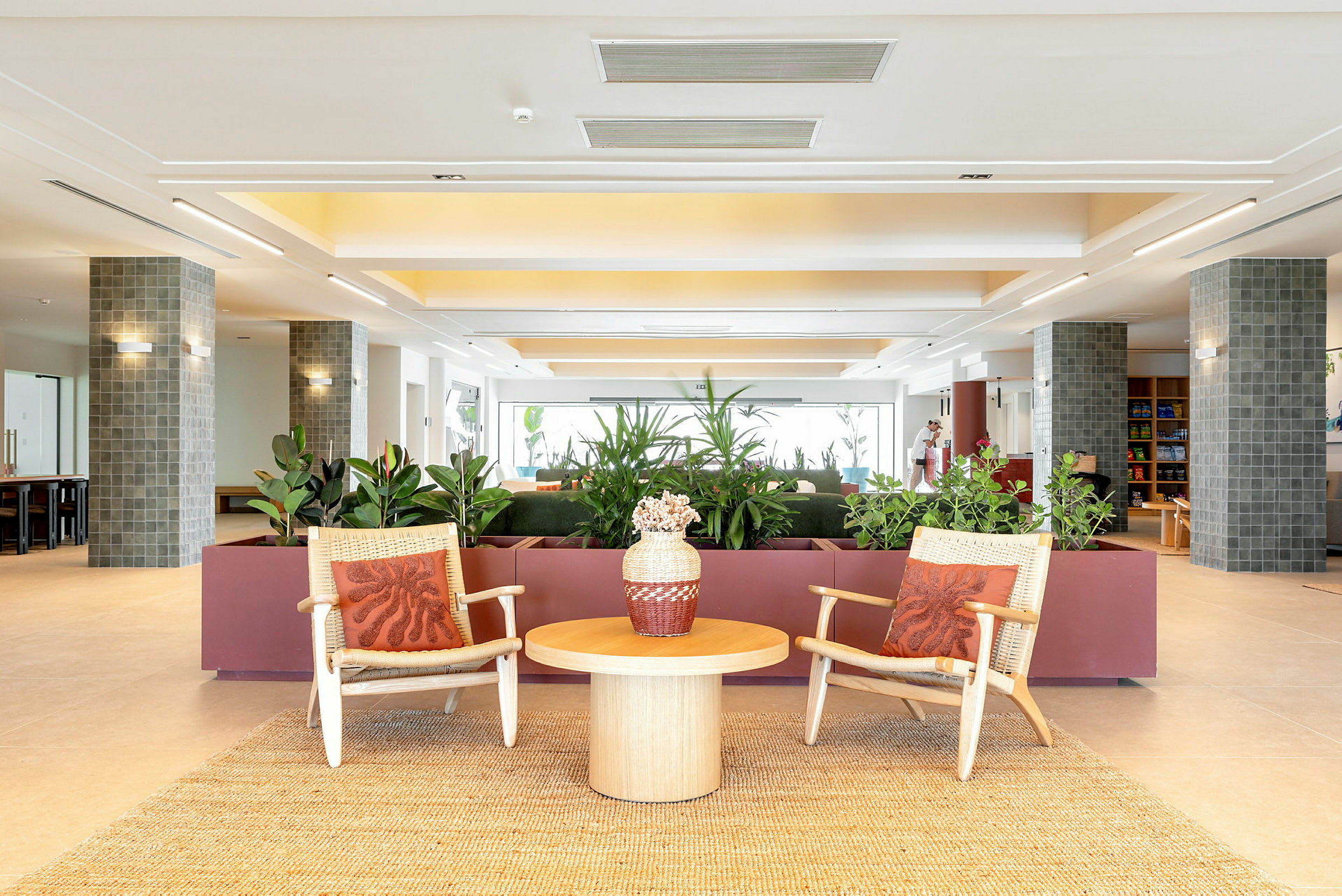 Bild av en modern hotellobby med två stolar, ett bord och växter i bakgrunden. (AI-genererad text)