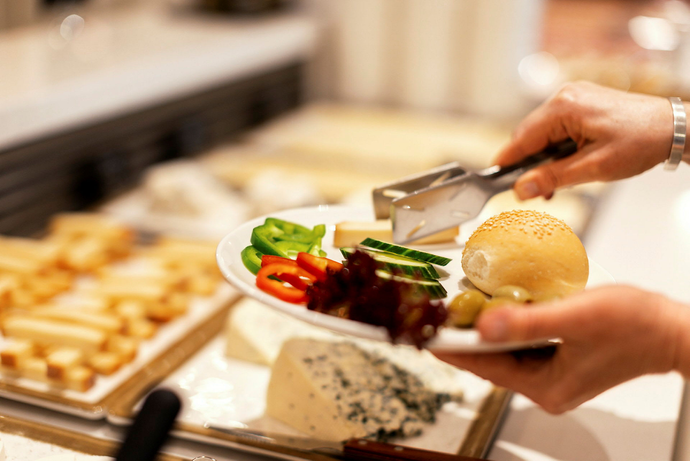 En hand håller en tallrik med grönsaker, bröd och ost. (AI-genererad text)