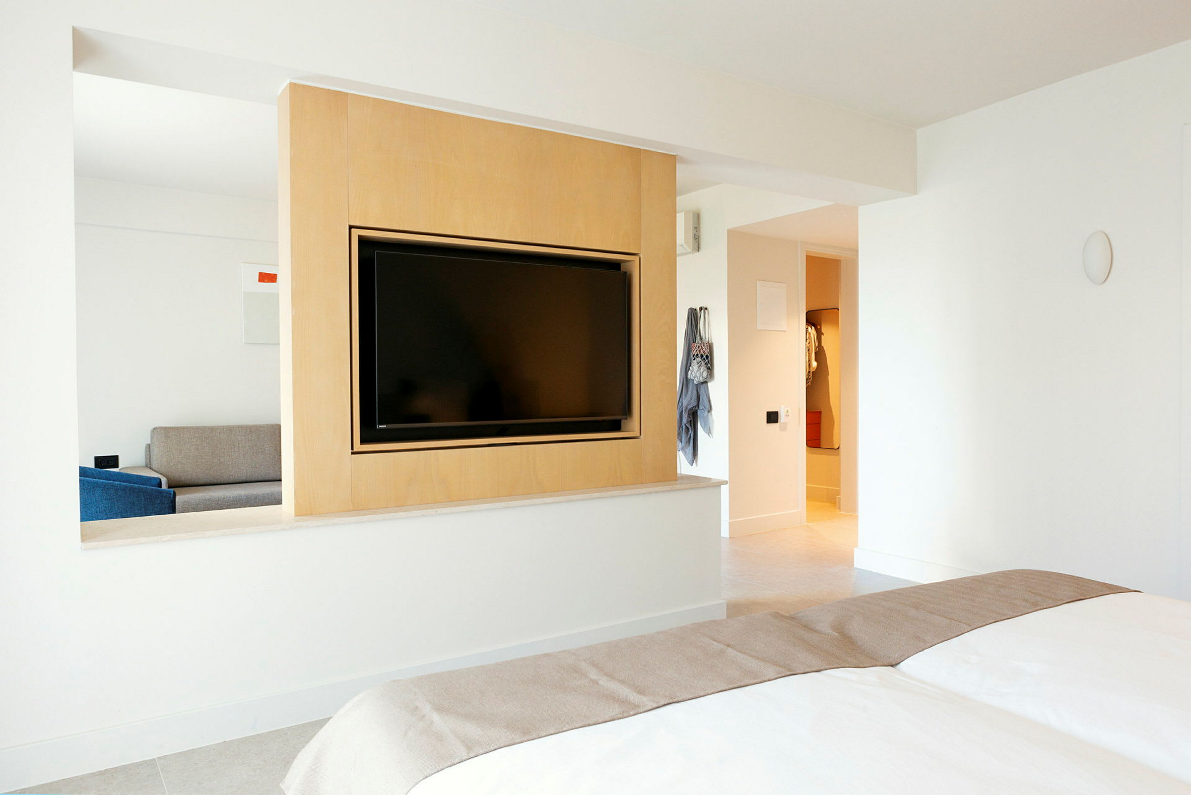 Ett hotellrum med en inbyggd vägg som innehåller en platt-TV och delar sovrummet från sällskapsdelen. (AI-genererad text)