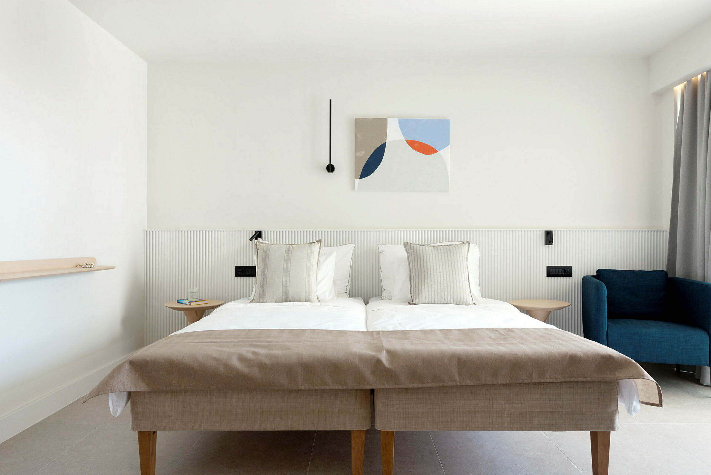 Ett hotellrum med en dubbelsäng, en blå fåtölj och modern väggdekor. (AI-genererad text)