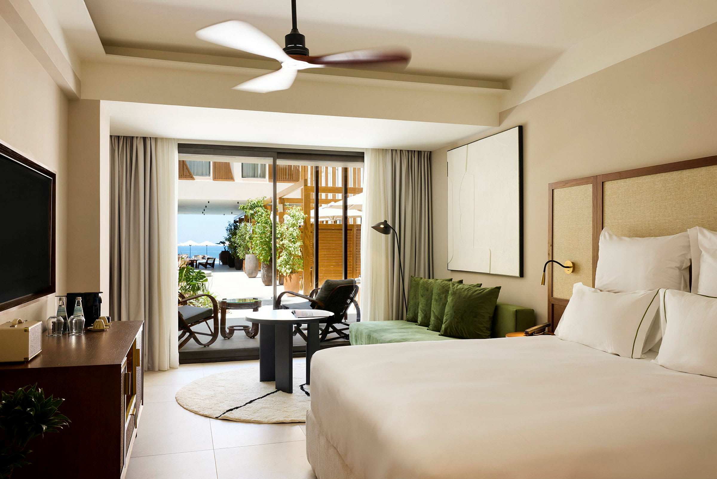 Hotellrum med modern inredning, en dubbelsäng, soffgrupp och stora glasdörrar som leder ut till en terrass. (AI-genererad text)