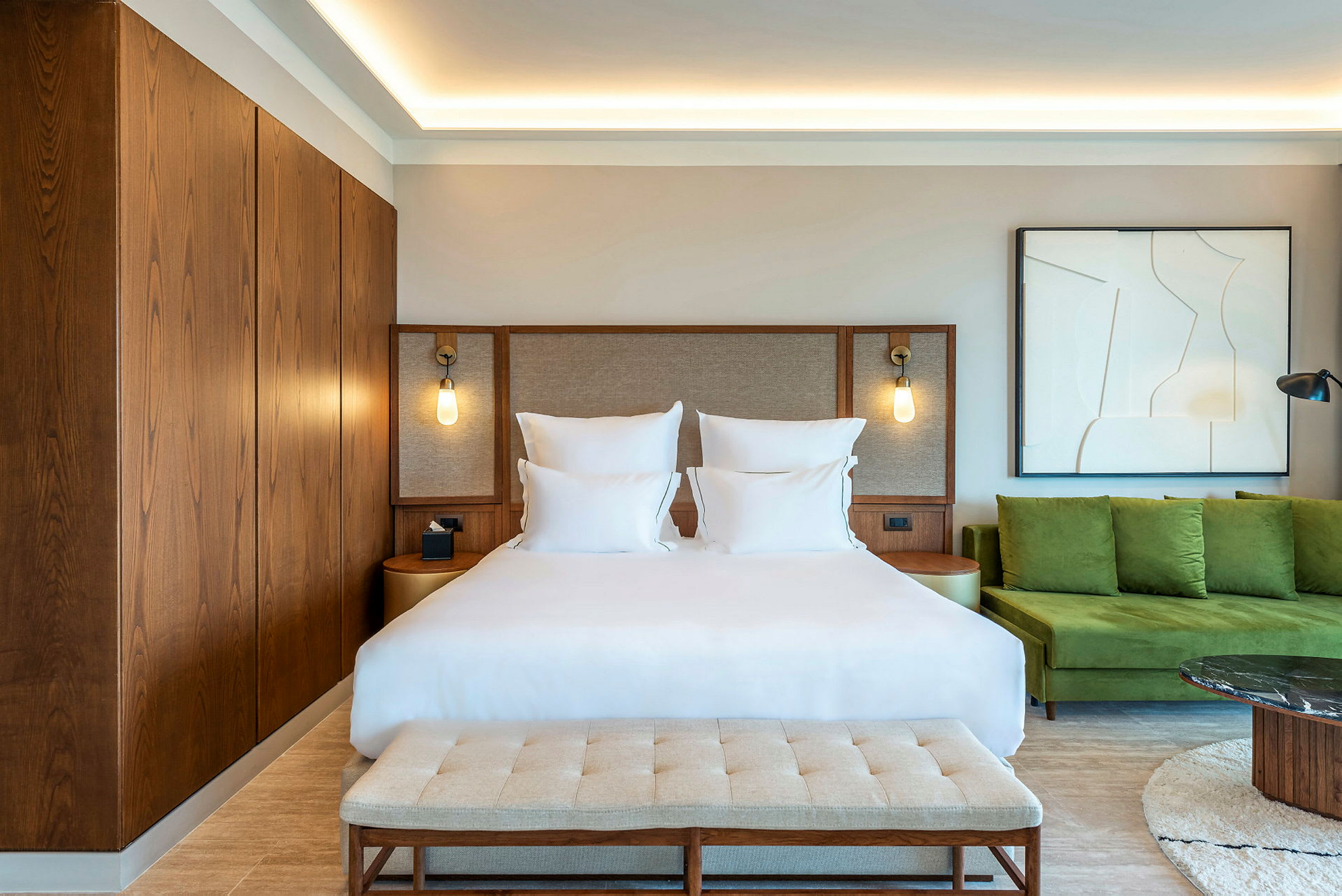 Hotellrum med en dubbelsäng, modern inredning och gröna sittmöbler. (AI-genererad text)