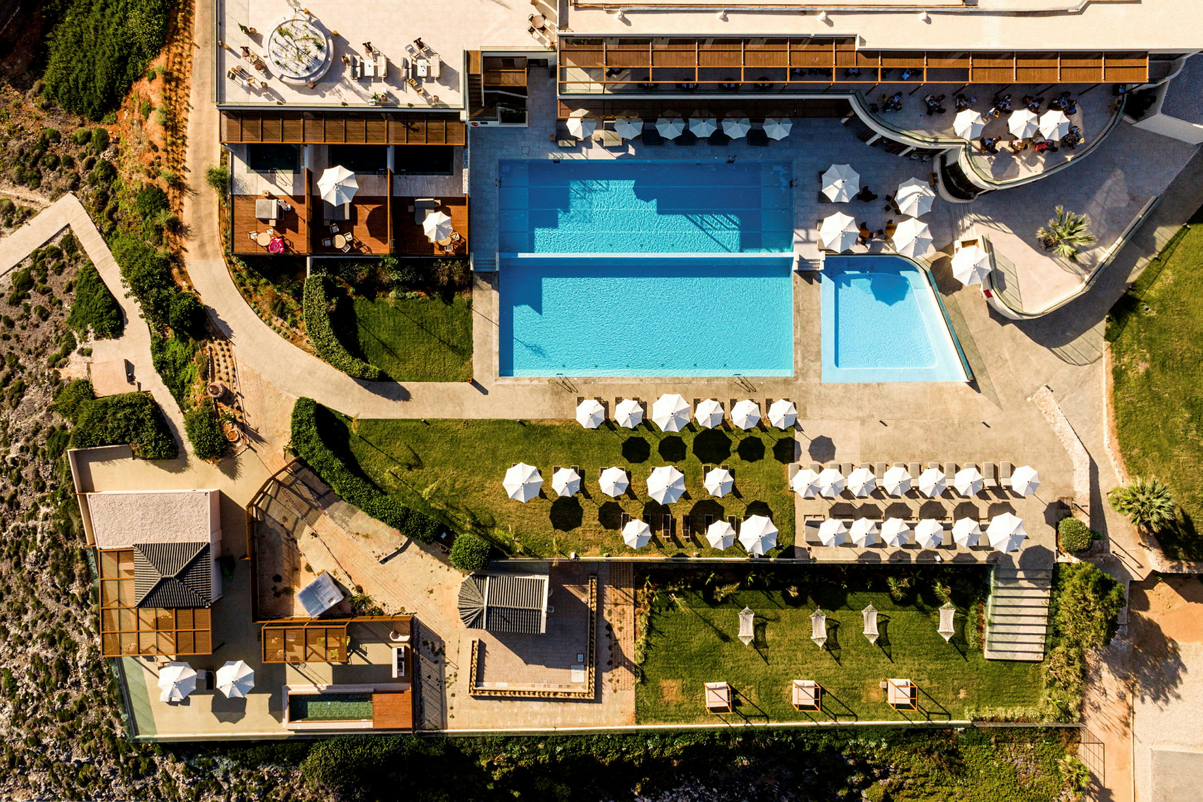 Flygfoto av en resort med pooler, solstolar och parasoller. (AI-genererad text)