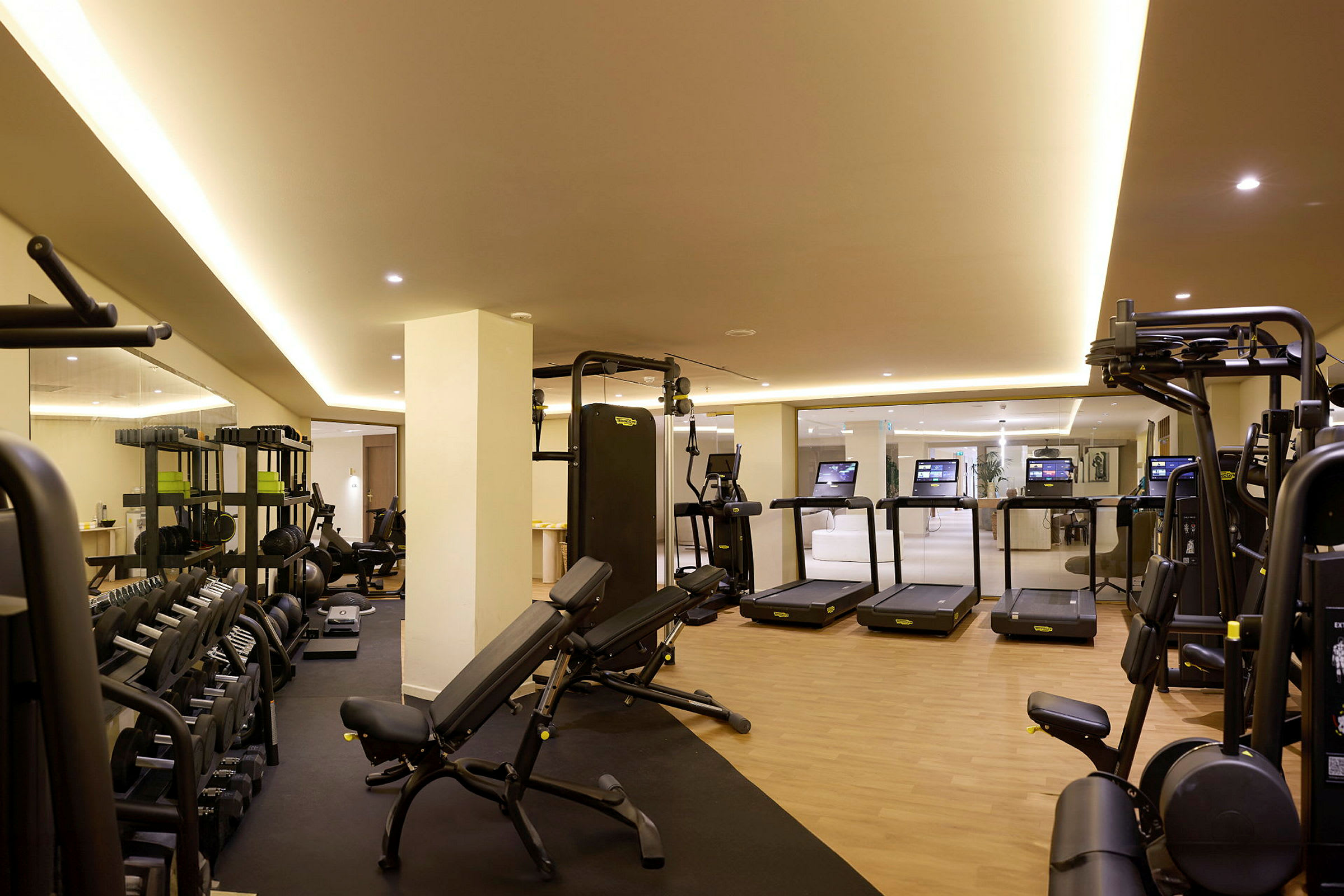 Ett gym med träningsmaskiner, löpband och vikter i en ljus interiör. (AI-genererad text)