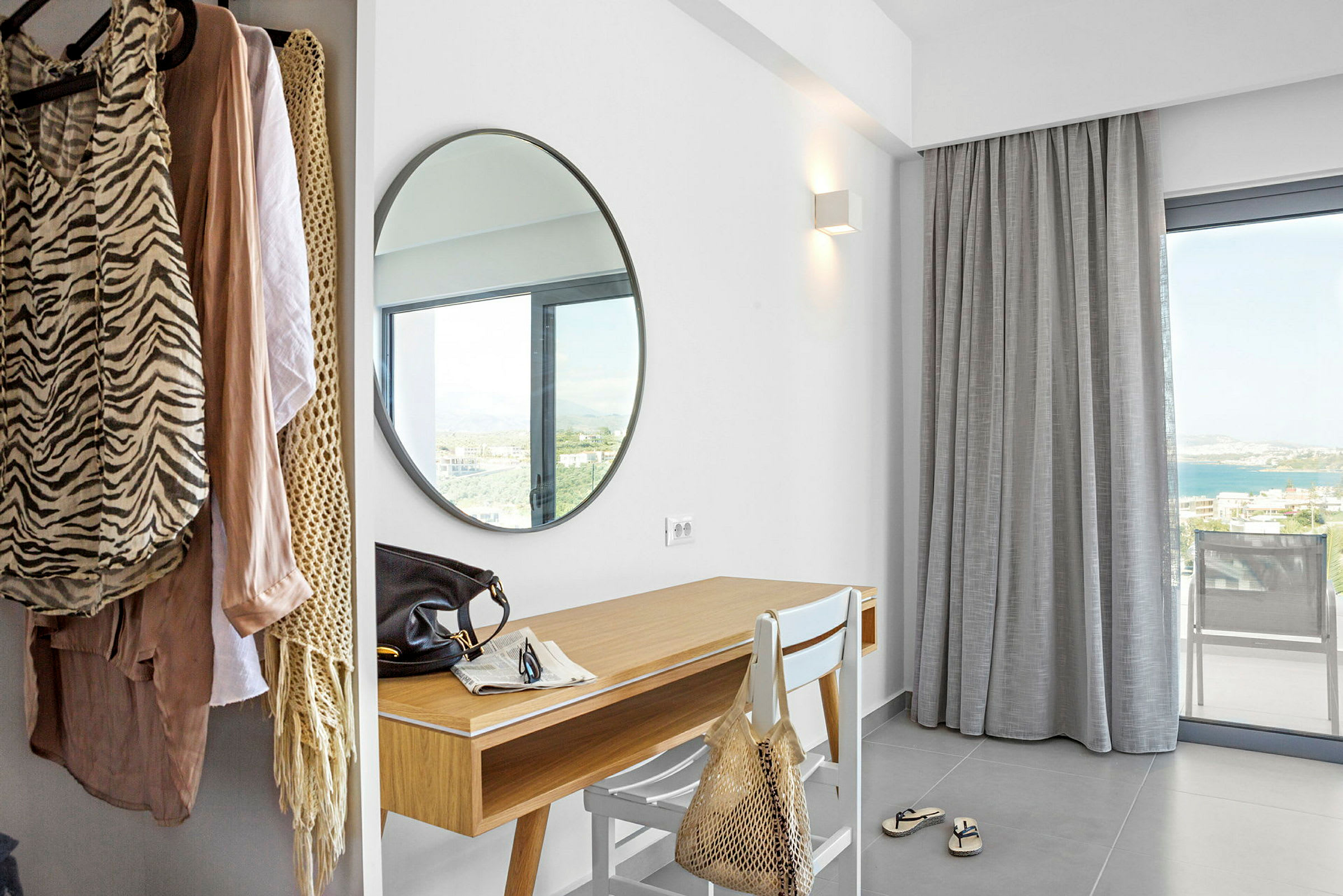 Hotellrum med rund spegel, skrivbord och klädhängare. (AI-genererad text)