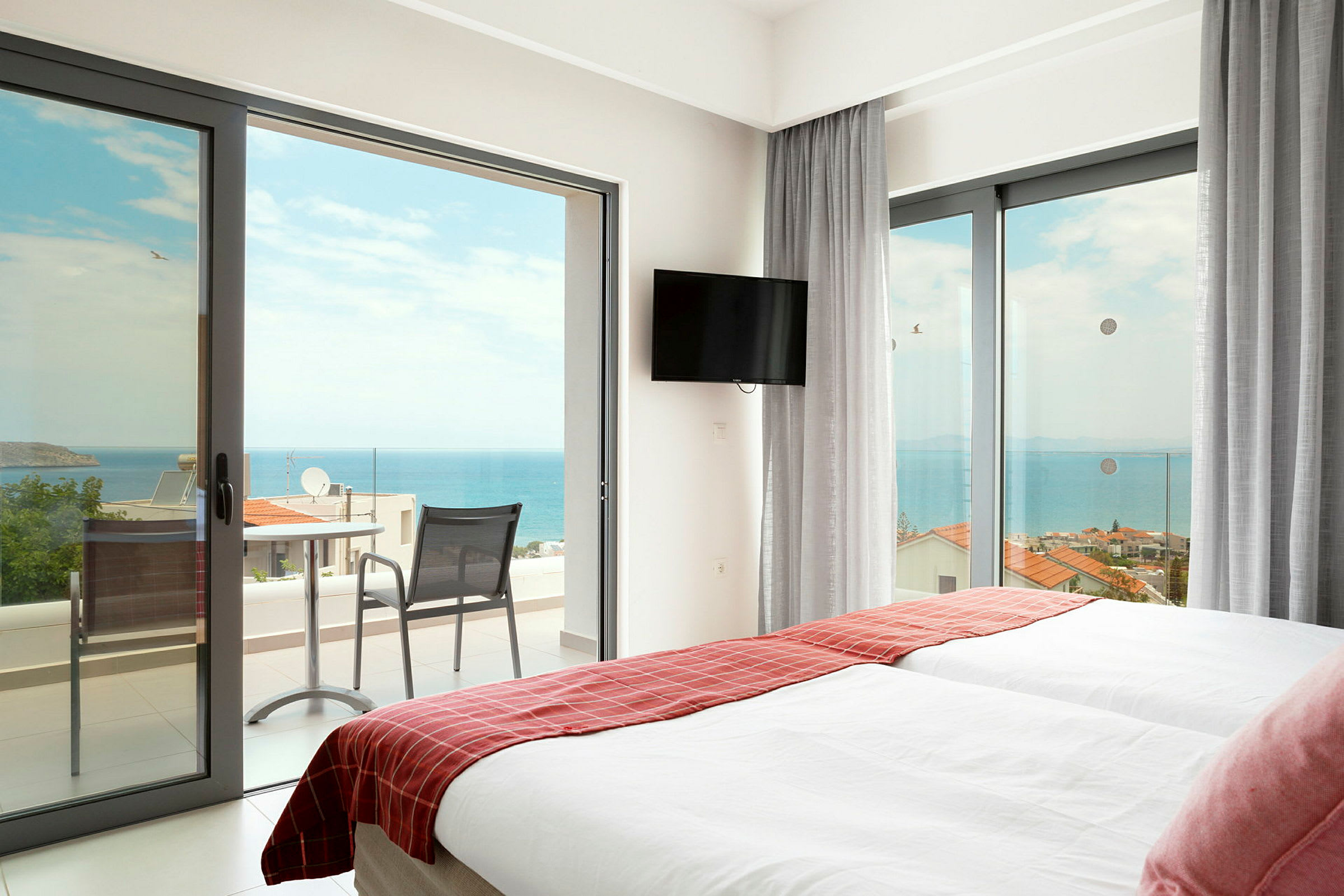Hotellrum med två sängar och dörrar till en balkong mot havet. (AI-genererad text)
