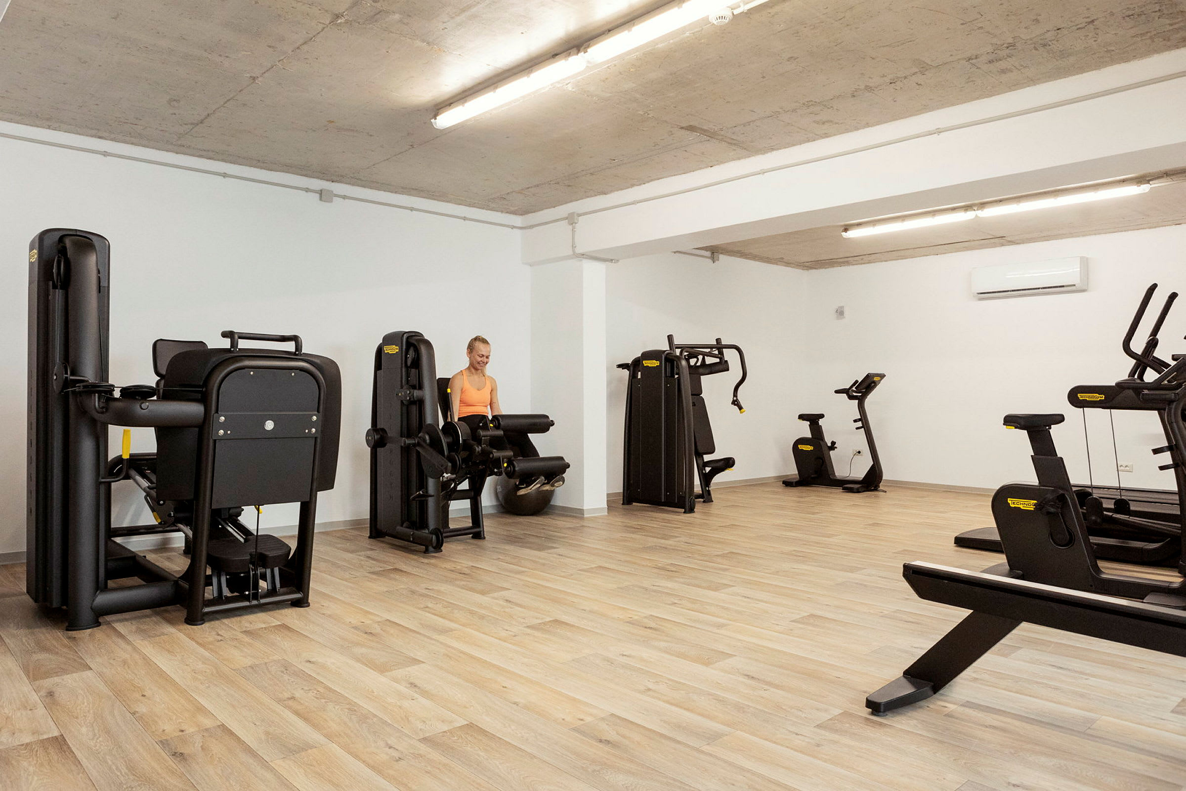 Ett gym med träpanelgolv och olika träningsmaskiner. (AI-genererad text)