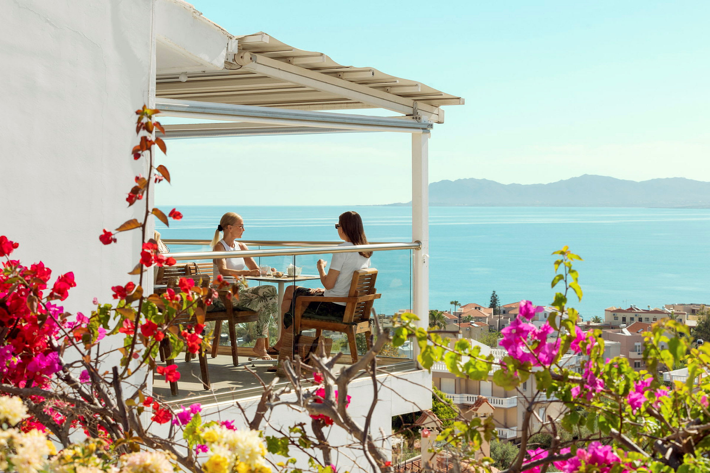 Två personer sitter på en terrass med utsikt över havet. (AI-genererad text)