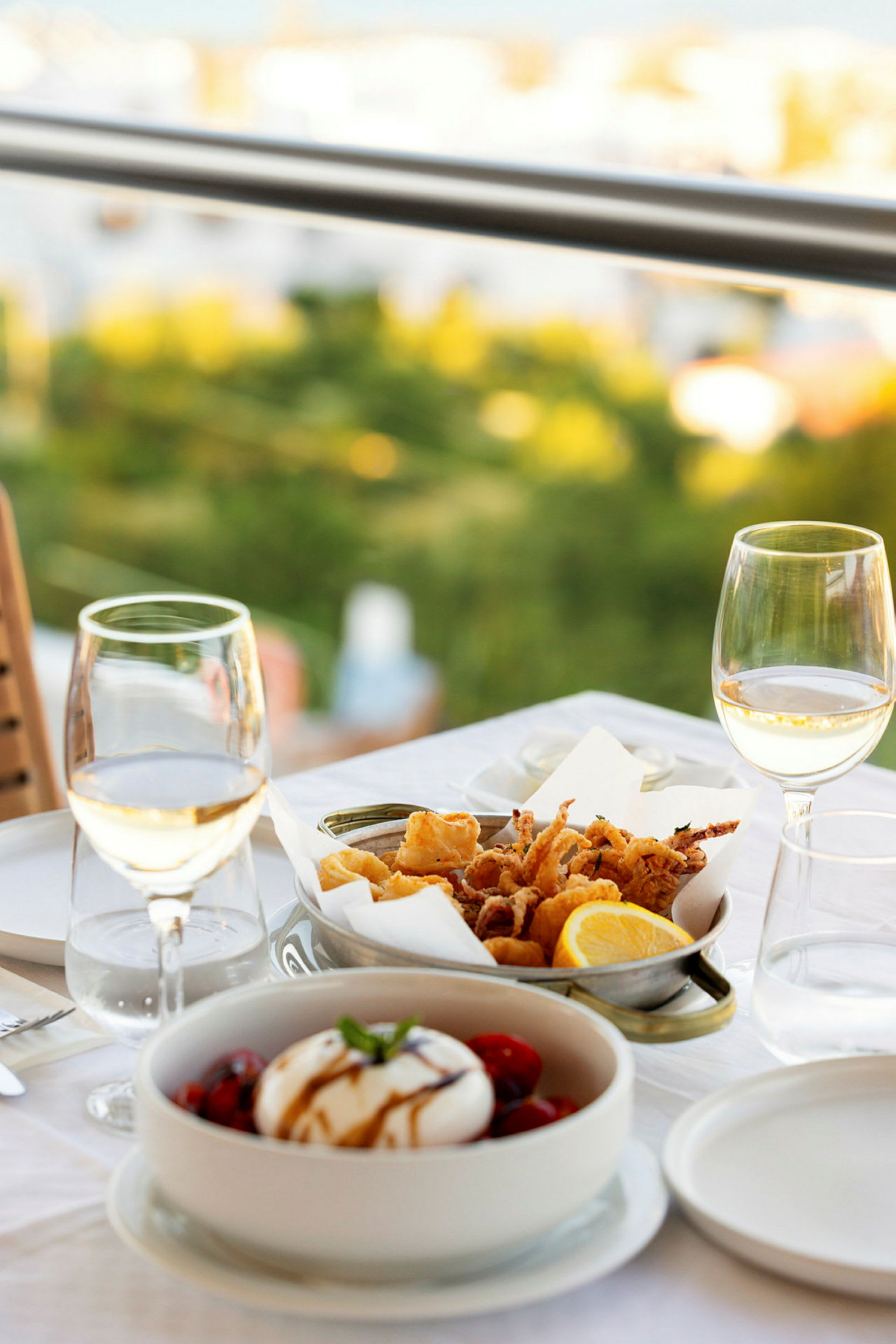 Ett dukat bord med vin, sallad och friterade skaldjur. (AI-genererad text)