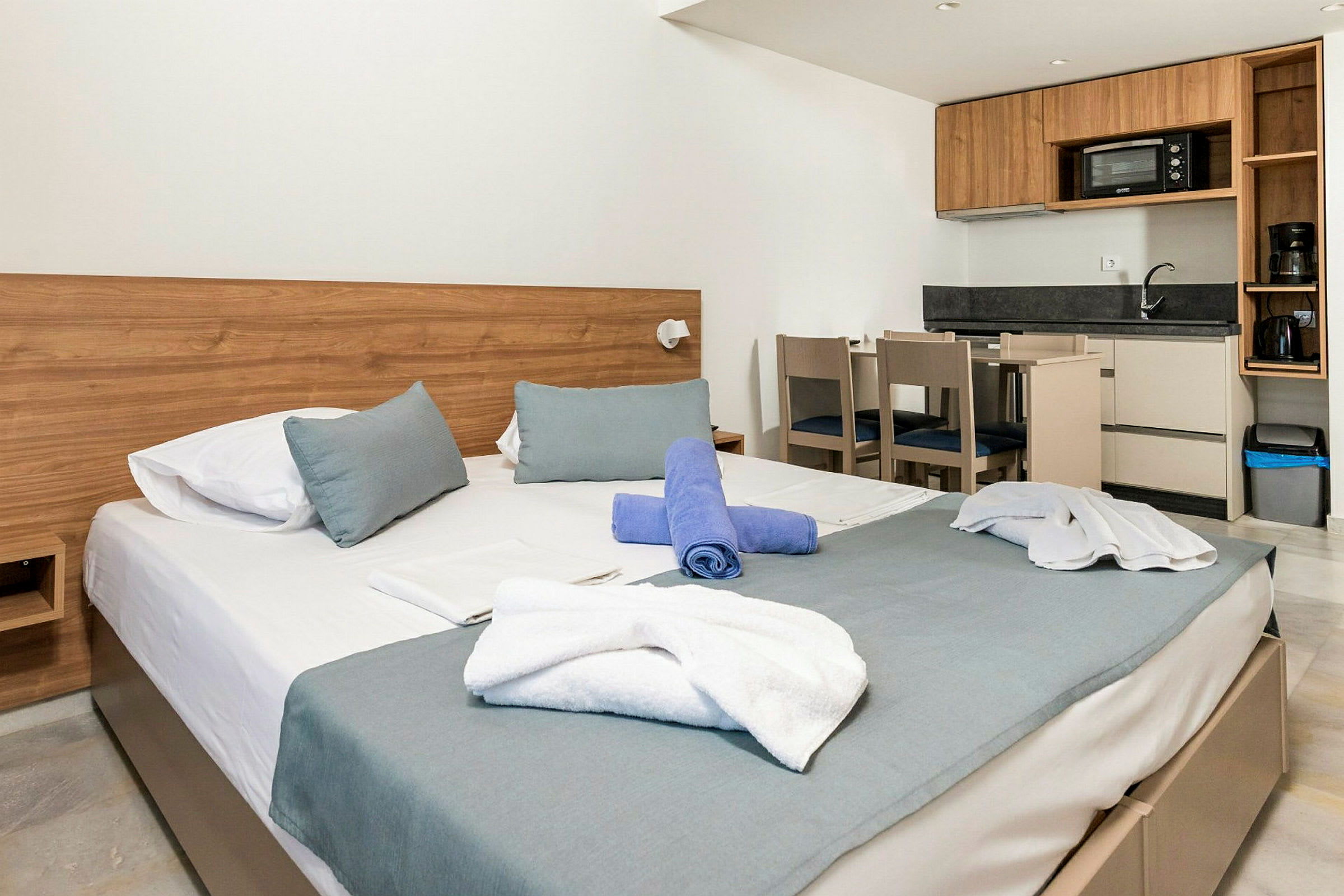 Modernt inrett hotellrum med säng, kök och matbord. (AI-genererad text)