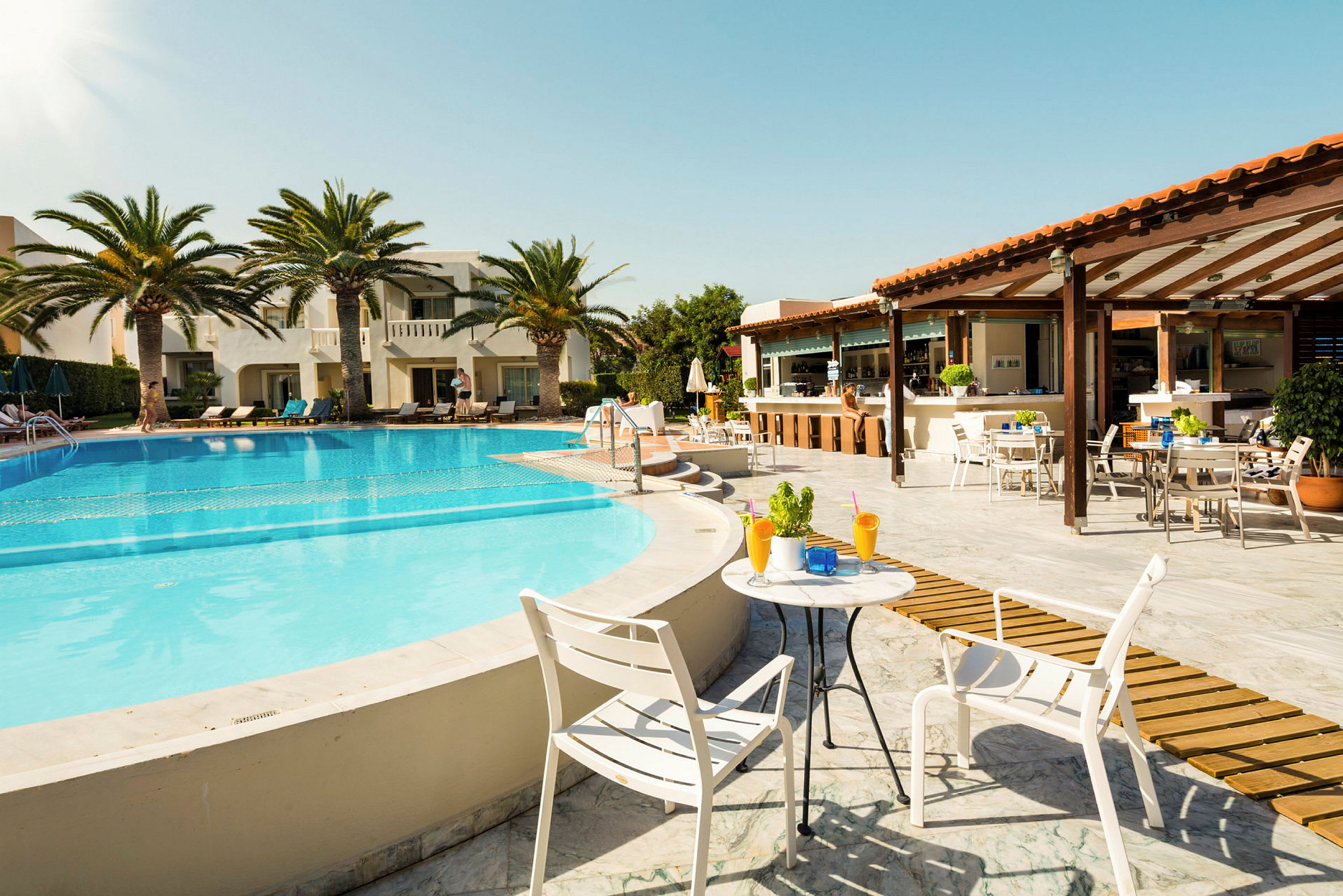 Bild av en pool med solstolar, palmträd och en restaurang i bakgrunden. (AI-genererad text)