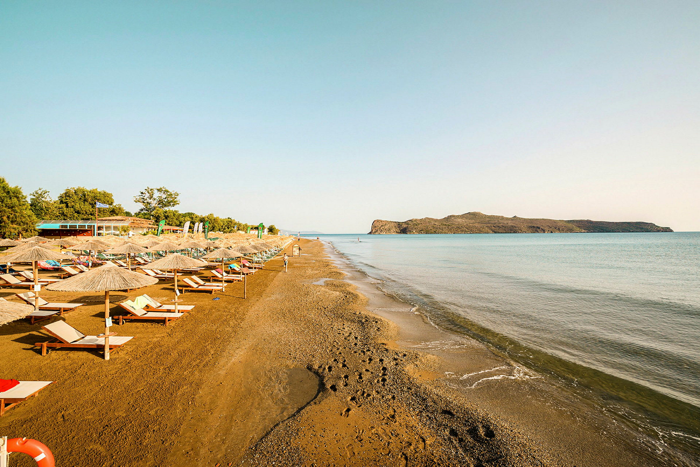 Strand med solstolar och parasoller längs vattnet. (AI-genererad text)