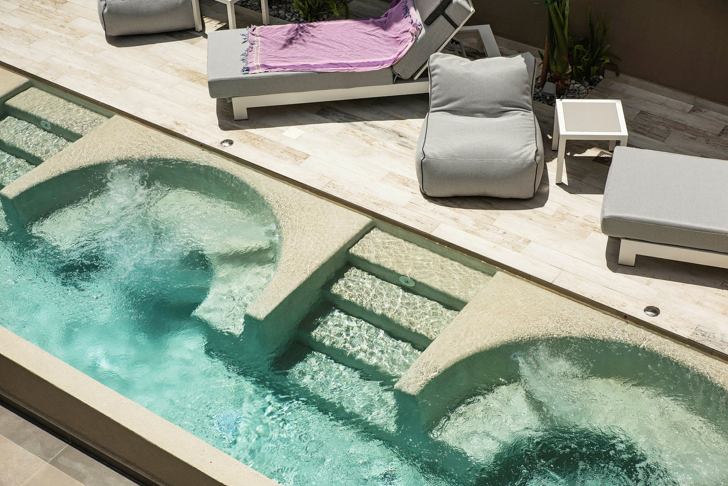 Bild av en pool med bubbelzoner och solstolar bredvid. (AI-genererad text)