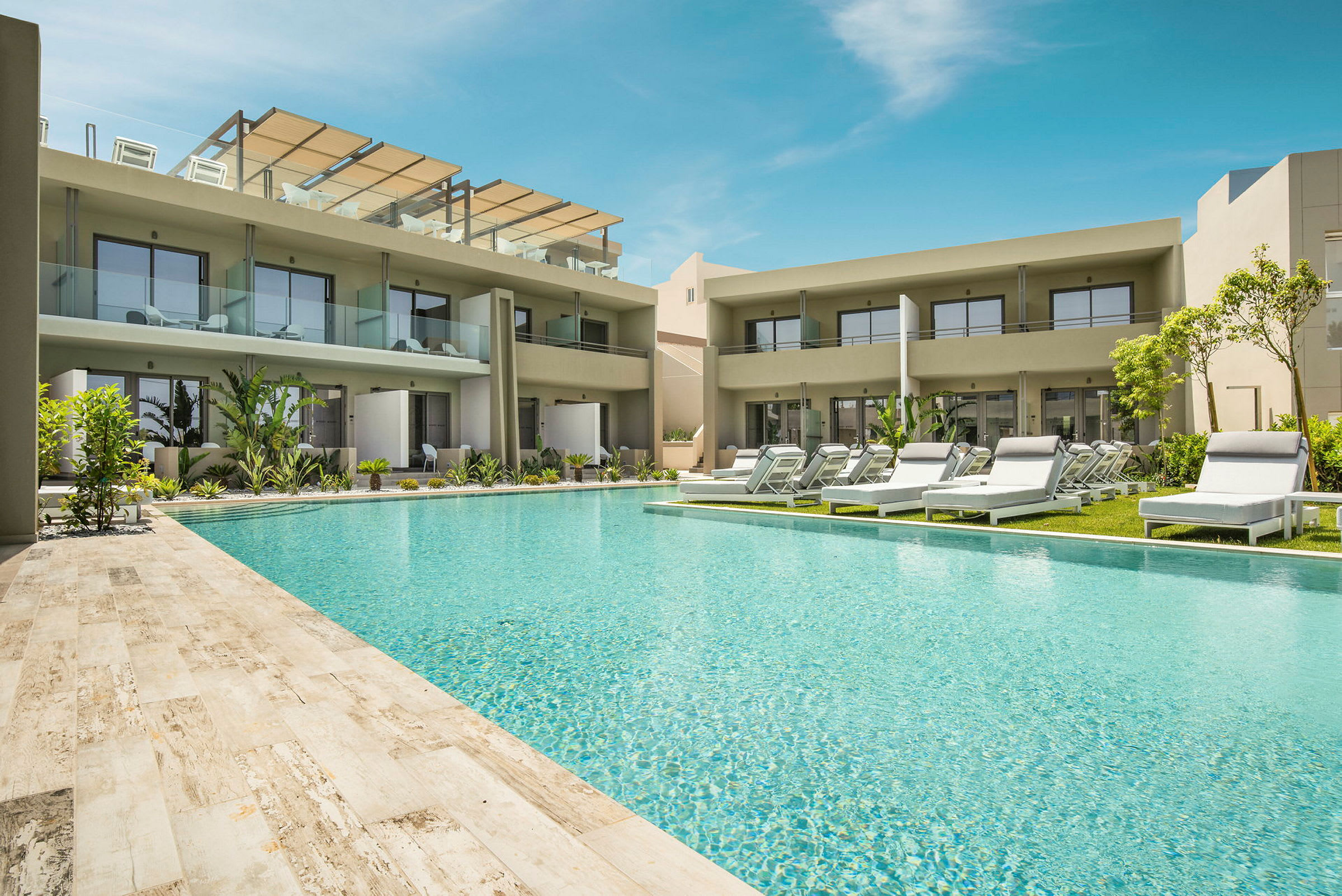 Hotellområde med pool, solstolar och moderna byggnader med balkonger. (AI-genererad text)