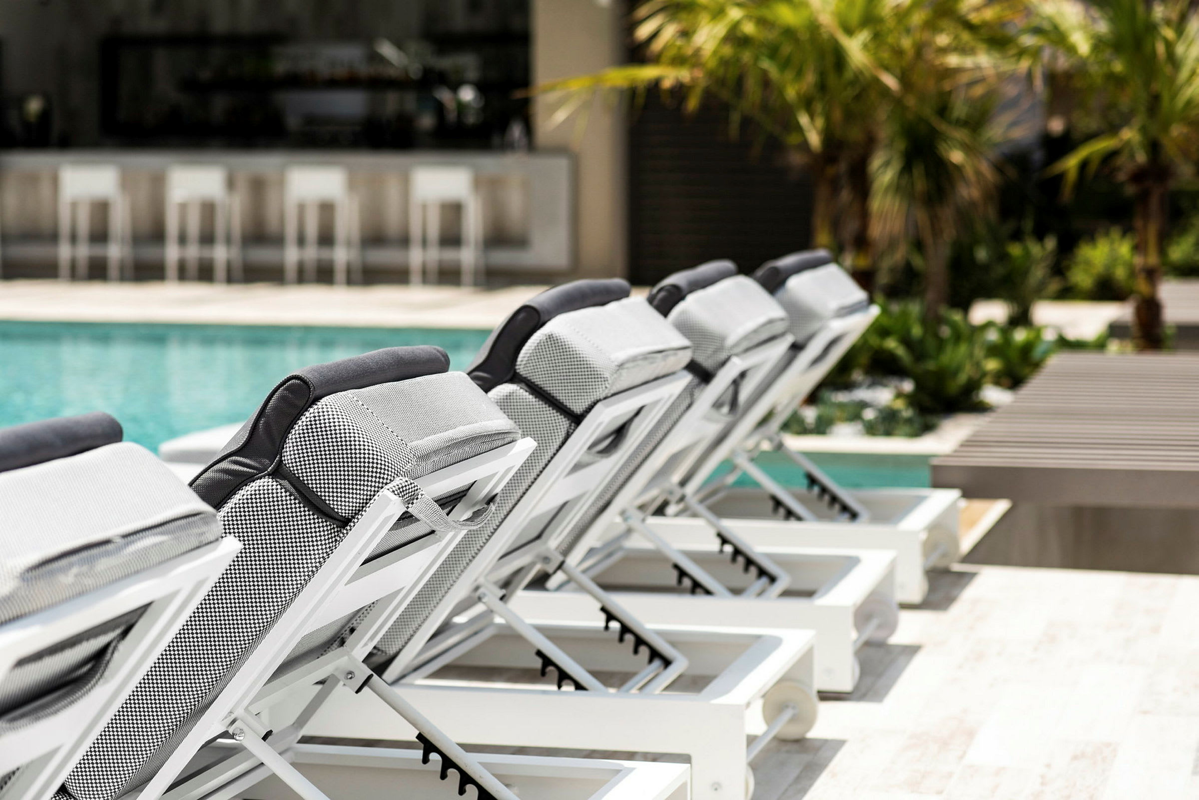 Solstolar vid en pool med en bar i bakgrunden. (AI-genererad text)