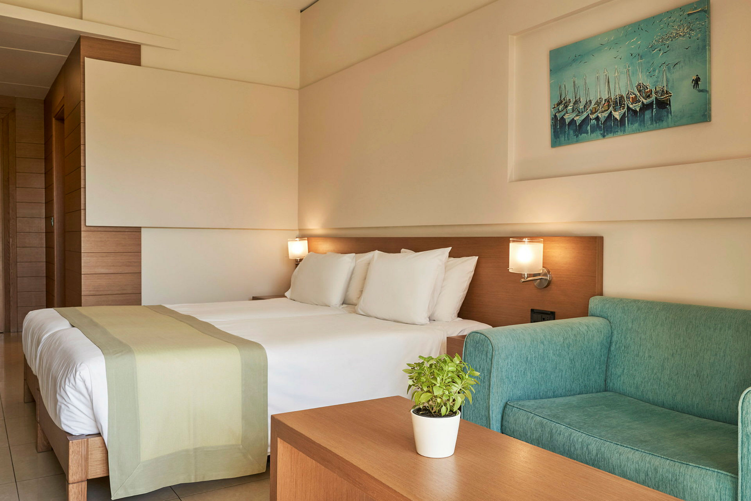 Ett hotellrum med en dubbelsäng, grön soffa och väggkonst. (AI-genererad text)