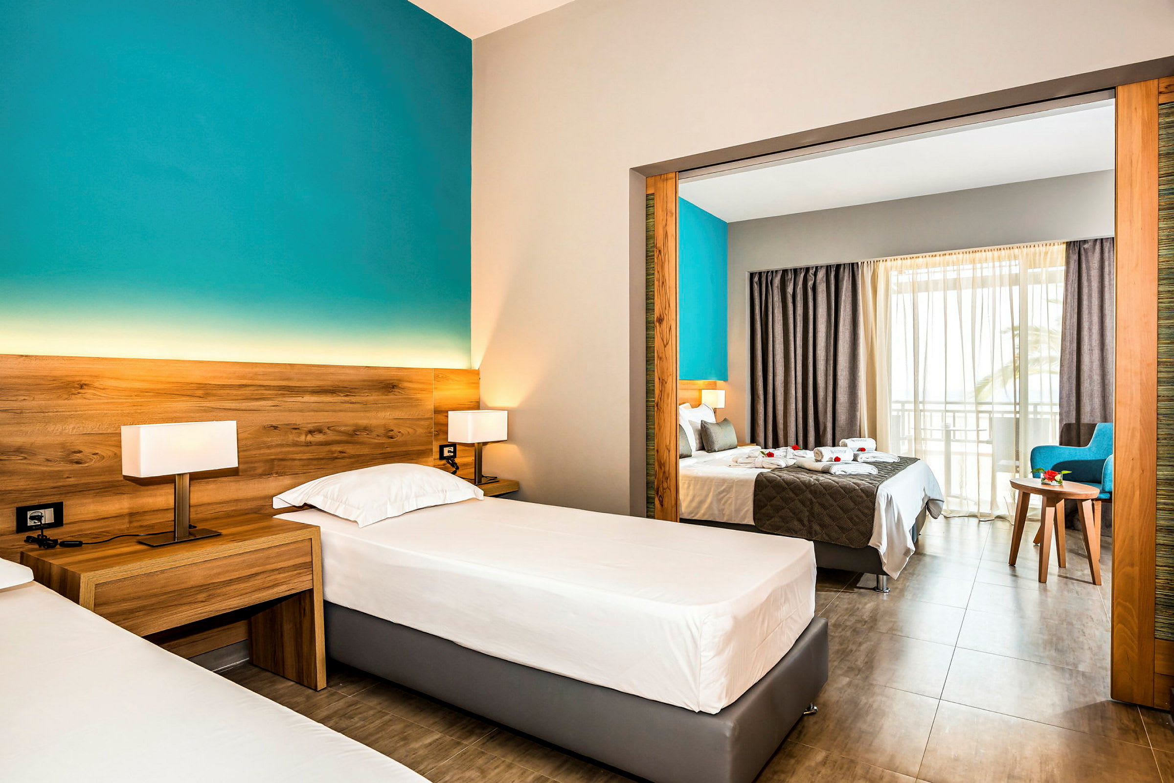 Hotellrum med två enkelsängar och visning mot dubbelrum genom en öppen portal. (AI-genererad text)