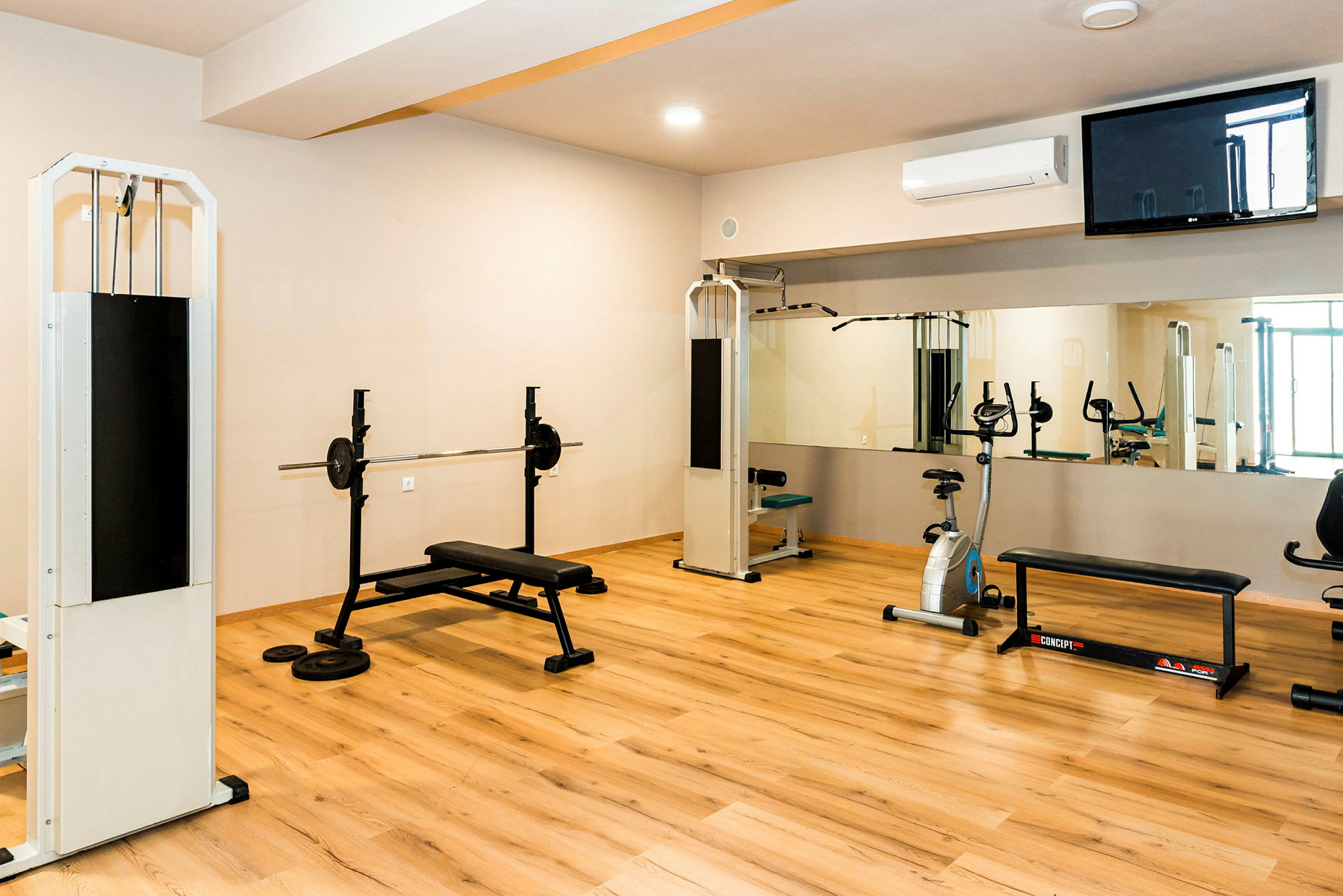 Ett gym med träningsutrustning, inklusive bänkpress, kabelmaskiner och motionscykel. (AI-genererad text)