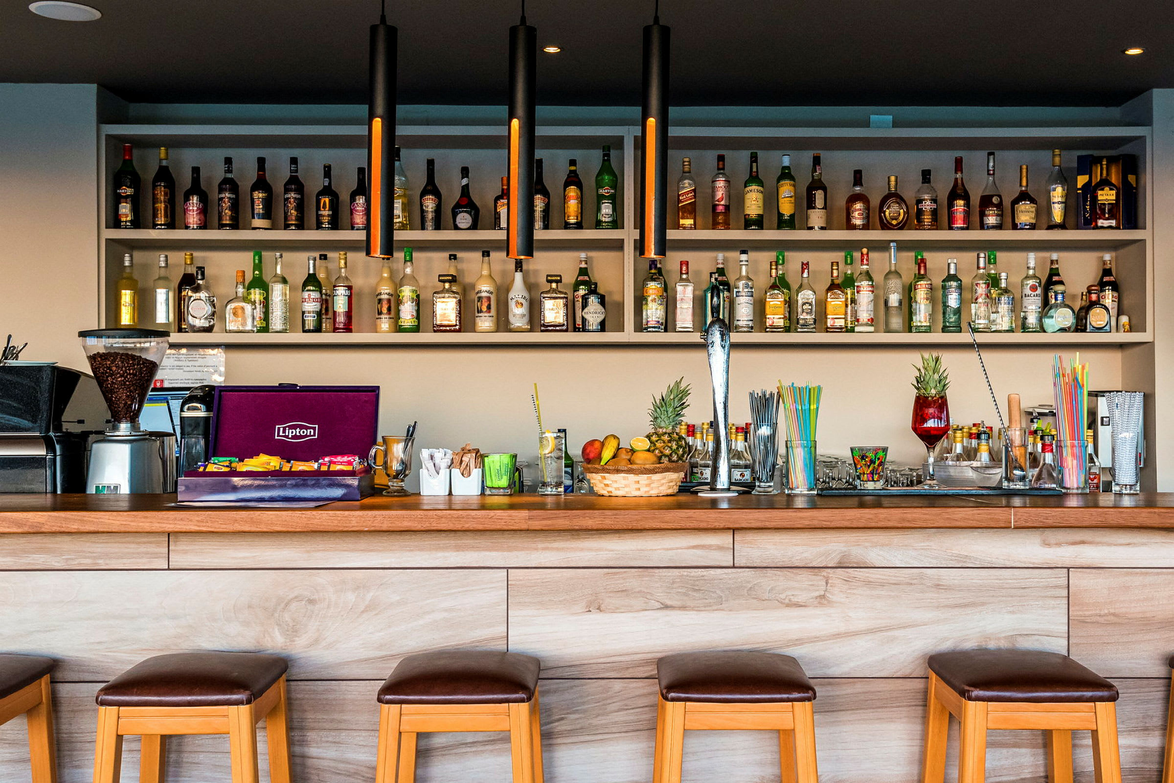 En bar med stolar, en hylla med olika drycker och ingredienser. (AI-genererad text)