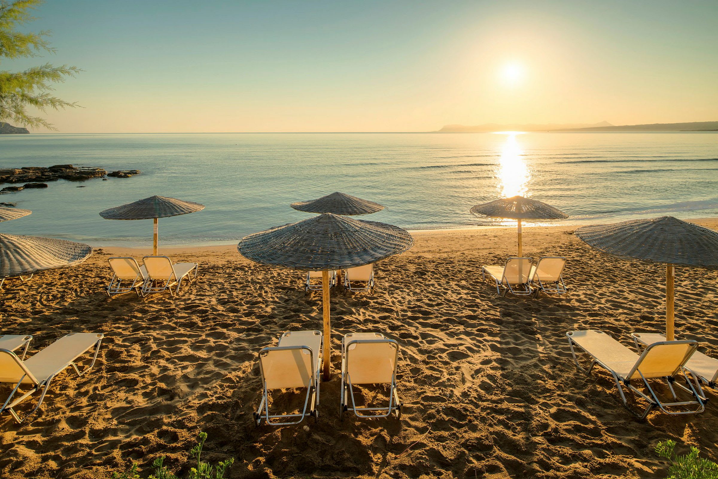 Strand med solparasoller och solstolar vid solnedgången. (AI-genererad text)
