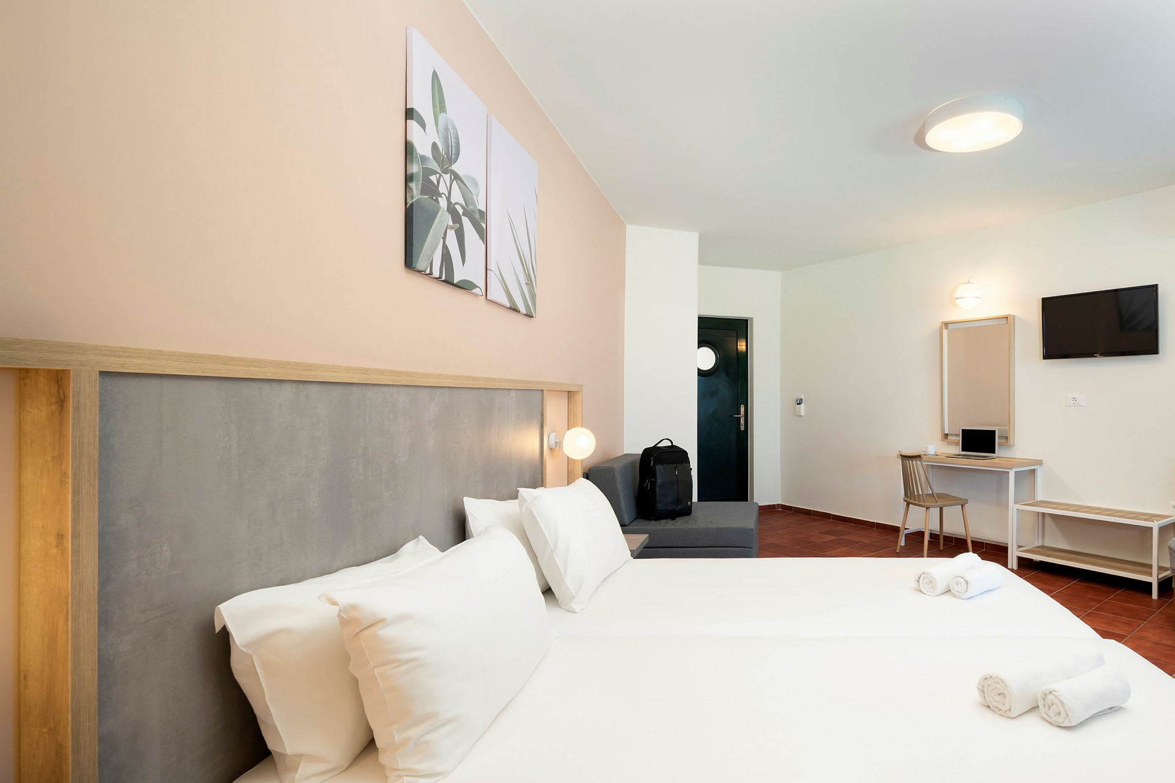 Hotelrum med dubbelsäng, sittplats, skrivbord och TV. (AI-genererad text)
