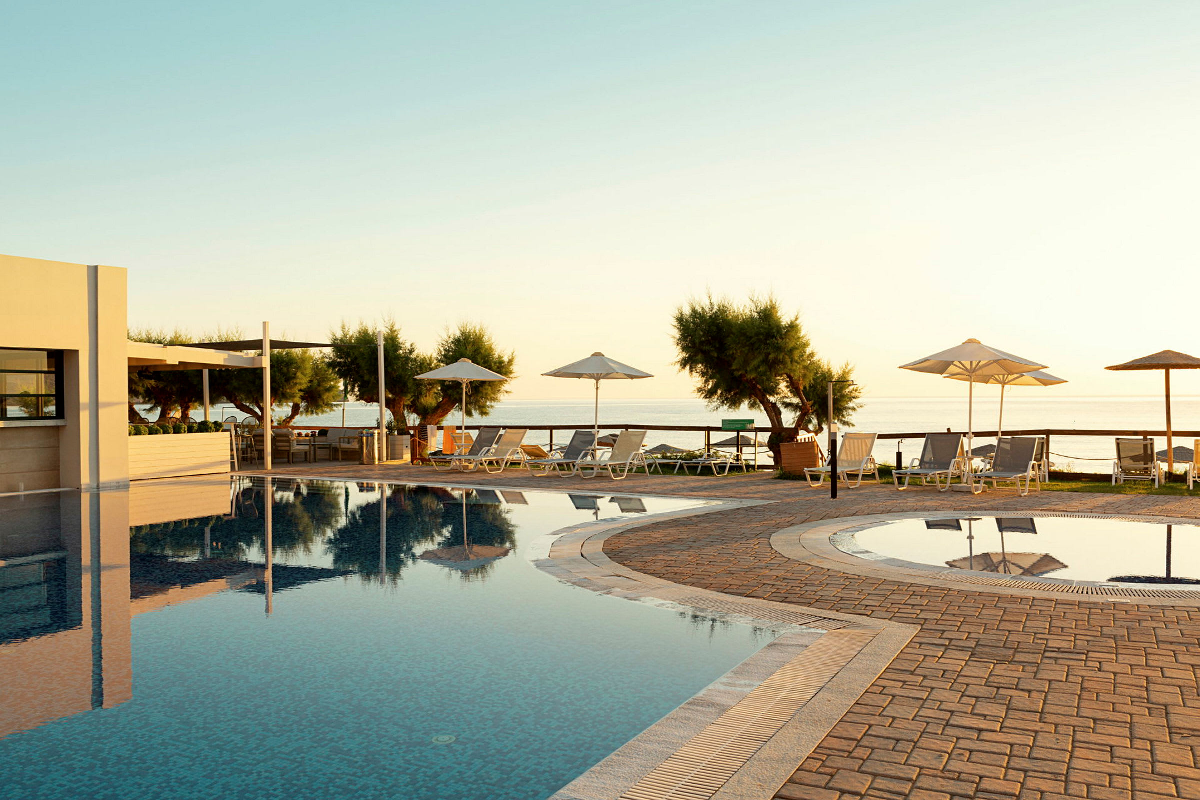 En pool vid havet med solstolar och parasoller. (AI-genererad text)