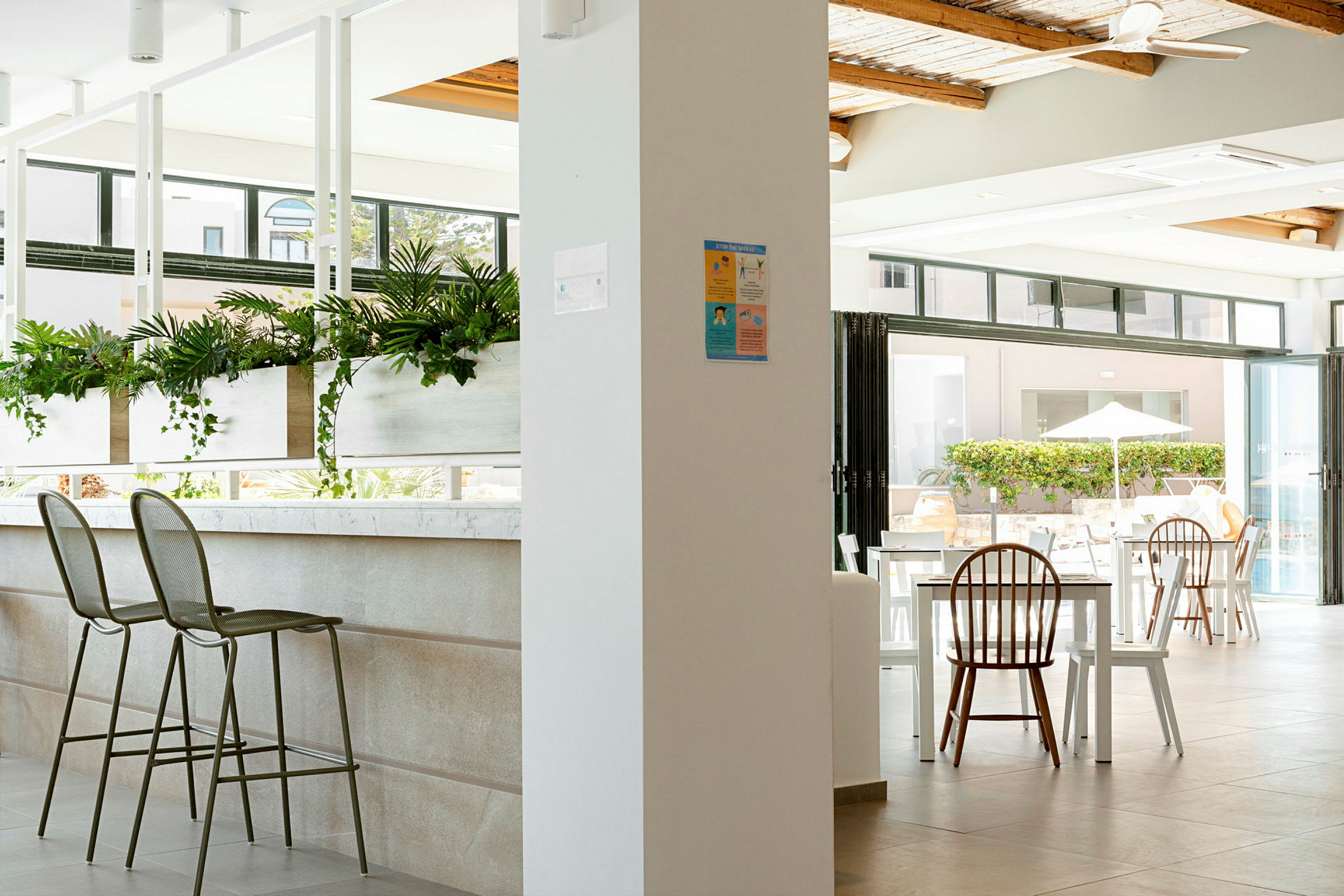 Interior av en modern och ljus restaurang med sittplatser och gröna växter. (AI-genererad text)