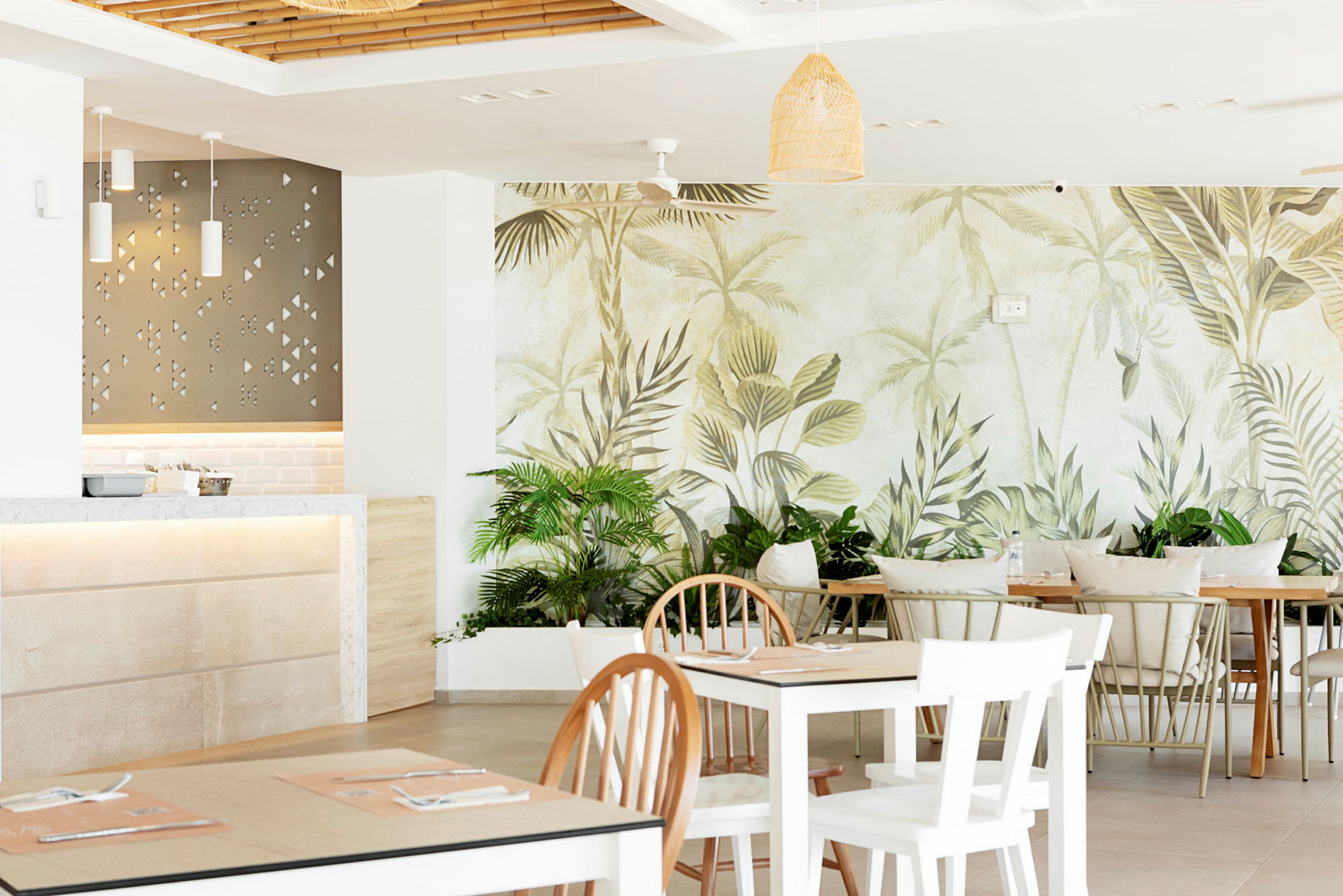Interiör av en restaurang med ljusa möbler och väggmålning av tropiska blad. (AI-genererad text)