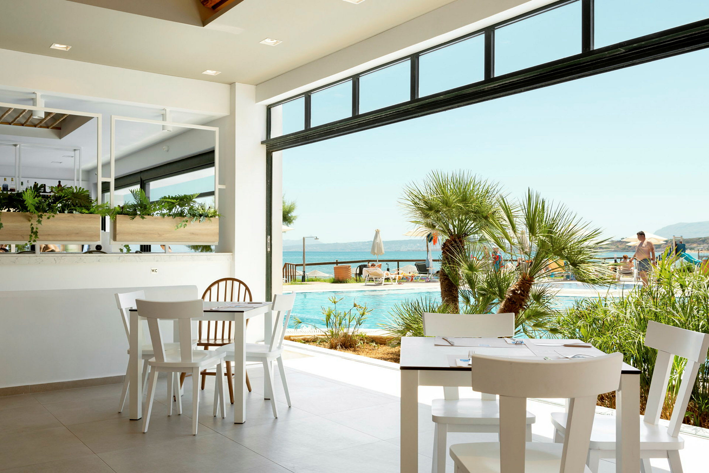 Utsikt från ett kafé mot en pool och havet. (AI-genererad text)