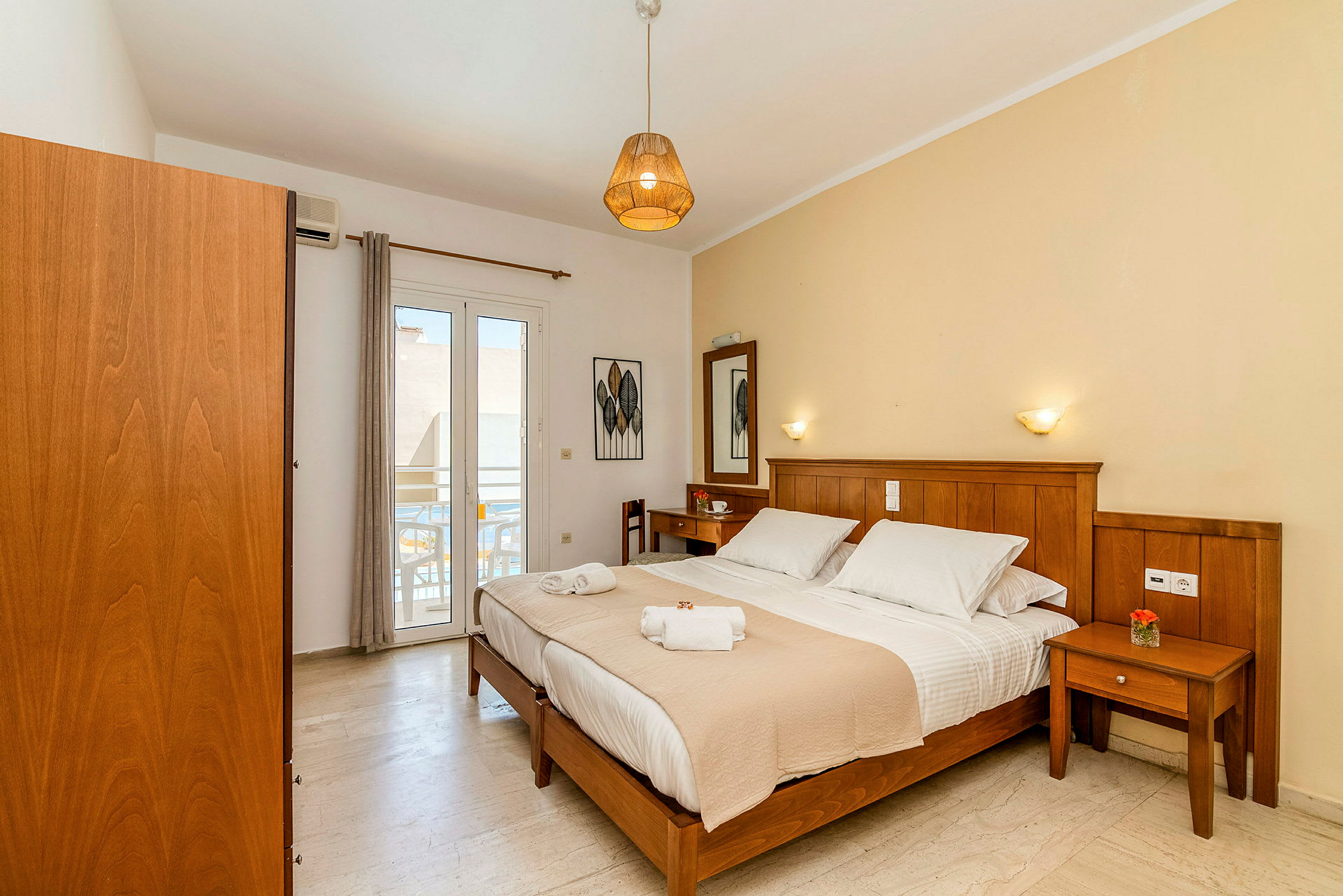 Ett hotellrum med en dubbelsäng, träinredning och en liten balkong. (AI-genererad text)