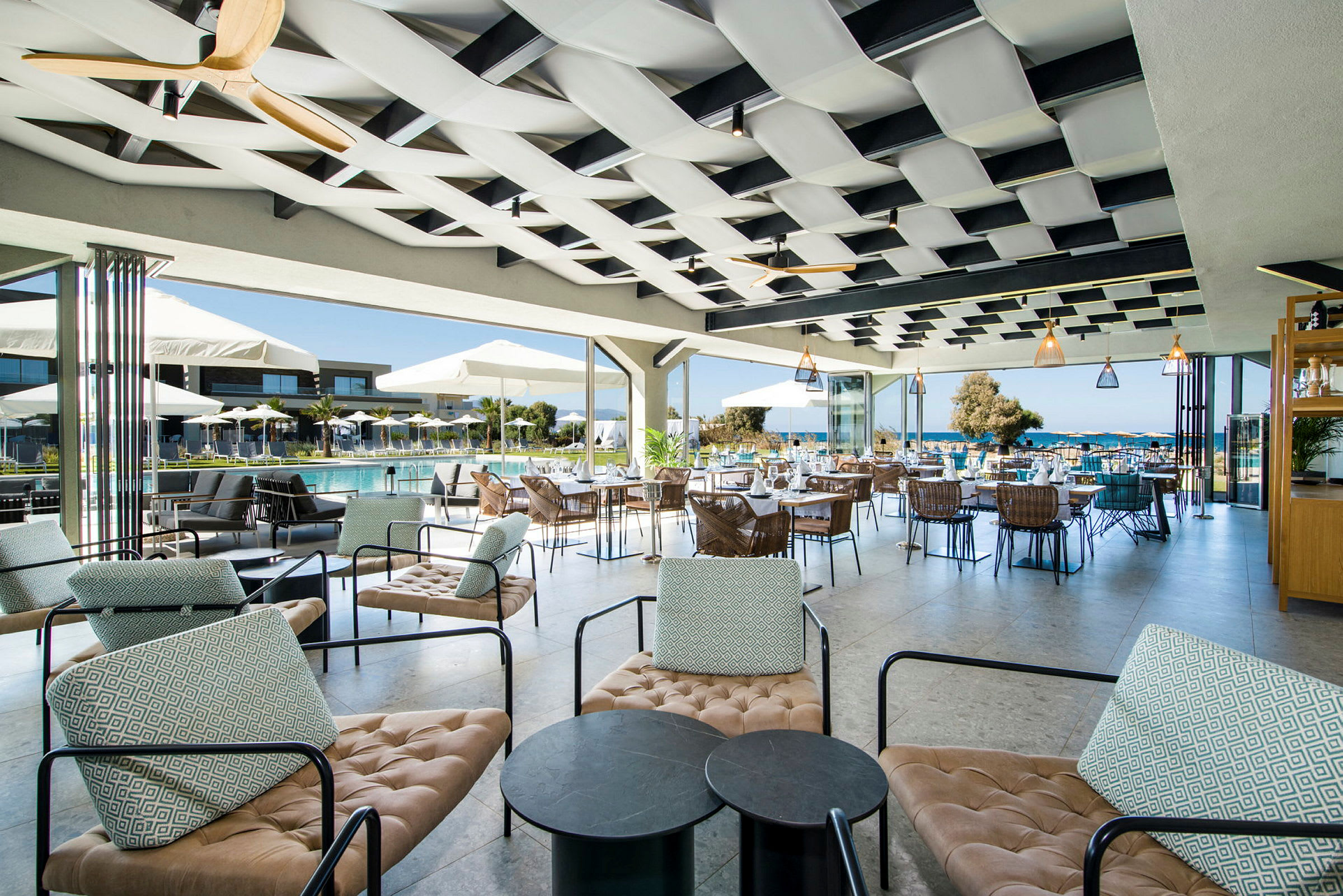 Utomhus sittplatser vid poolområdet på ett hotell, med moderna möbler och utsikt över havet. (AI-genererad text)