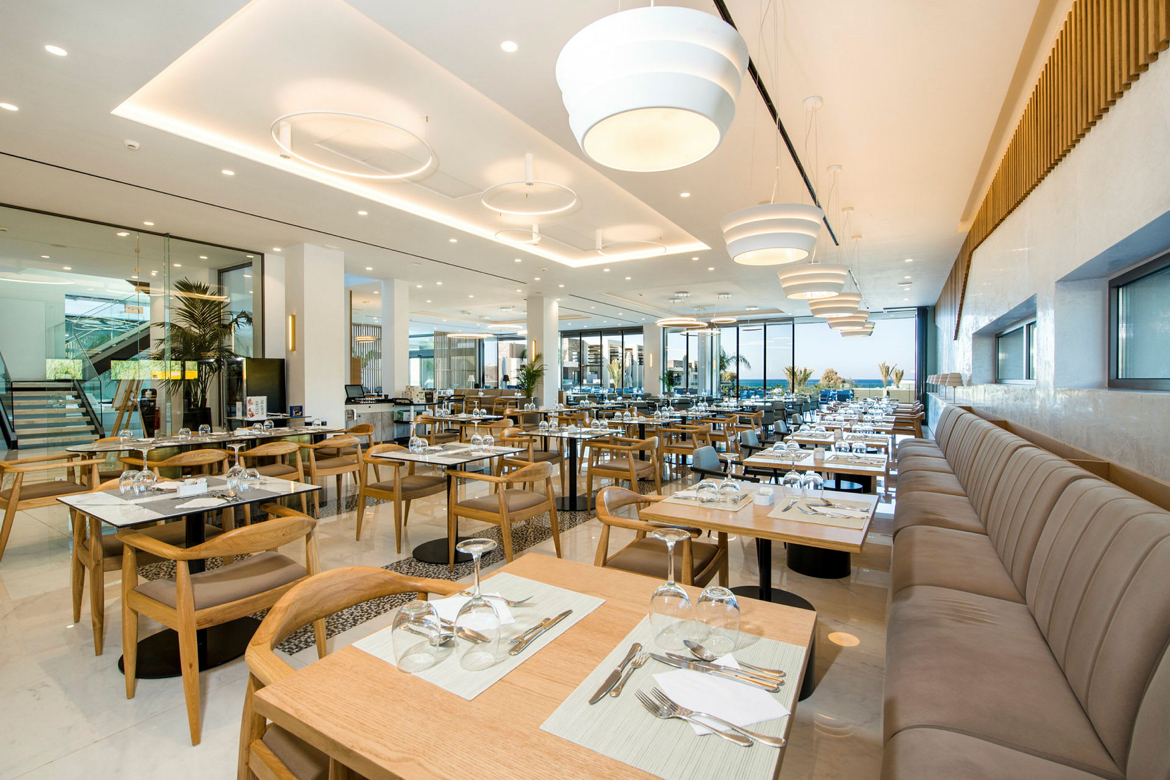 En modern restaurang med uppställda bord och stolar samt stora fönster. (AI-genererad text)