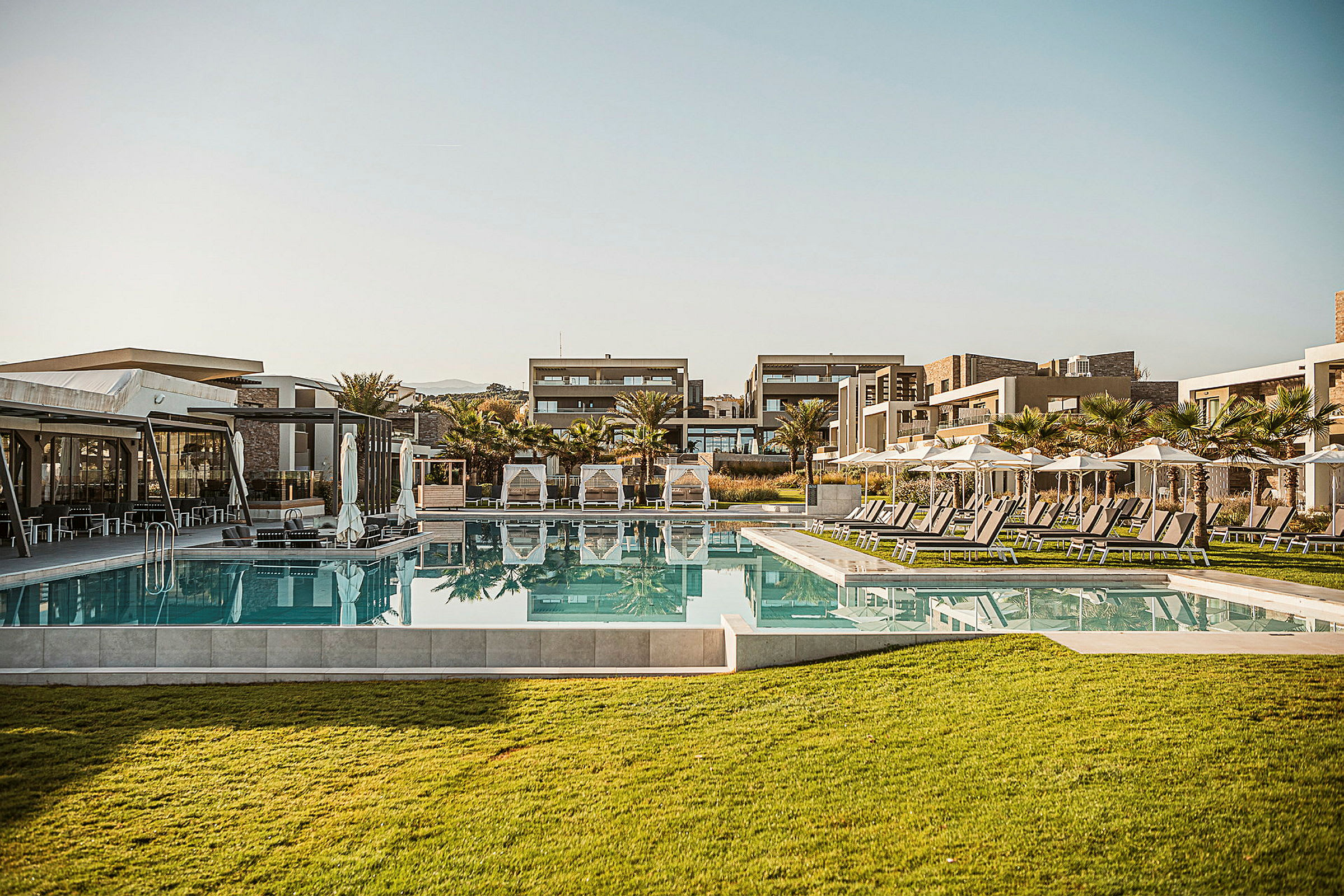 Bild på ett hotellområde med pool, solsängar och moderna byggnader. (AI-genererad text)
