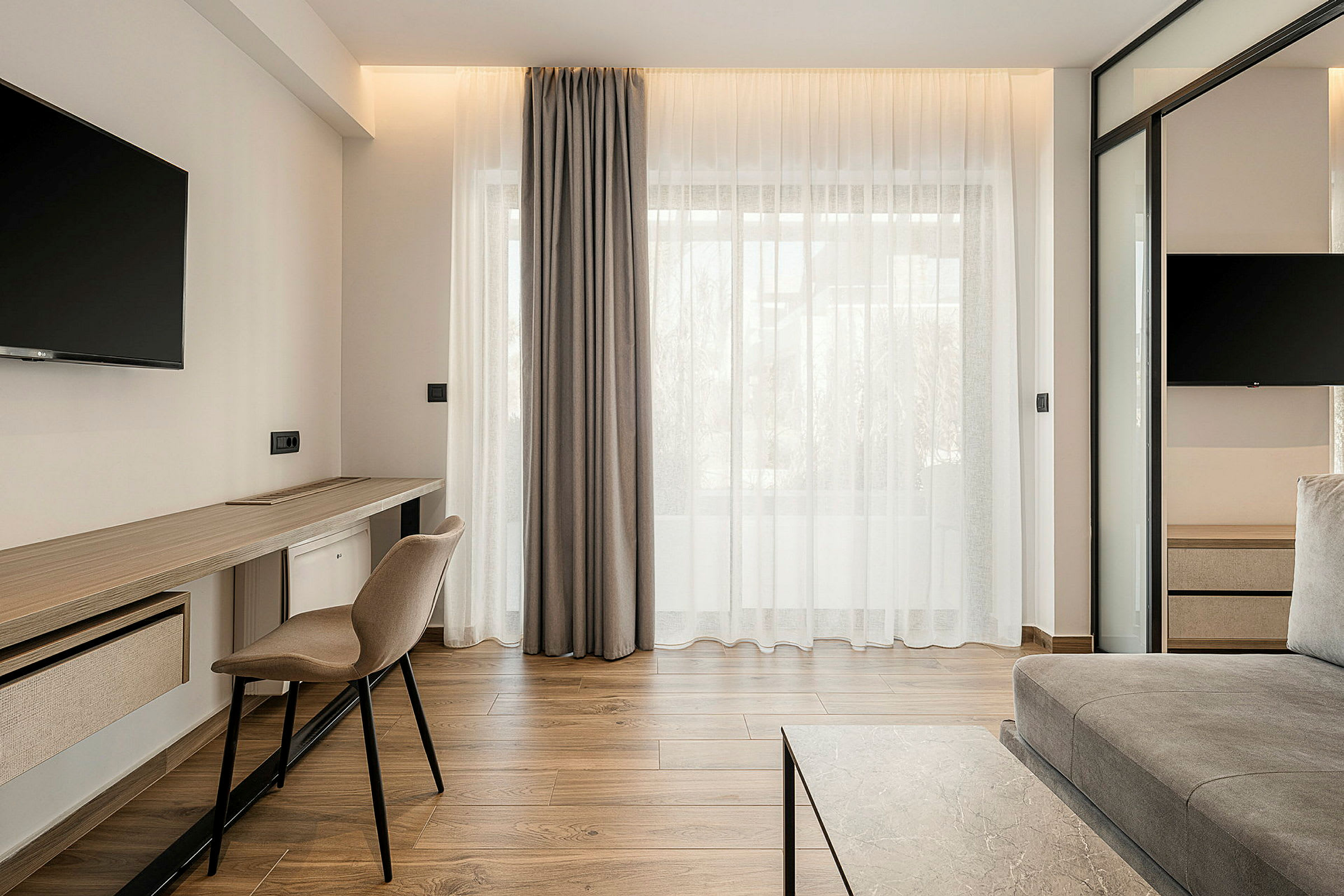 Modernt möblerat hotellrum med sittmöbler, skrivbord och TV. (AI-genererad text)