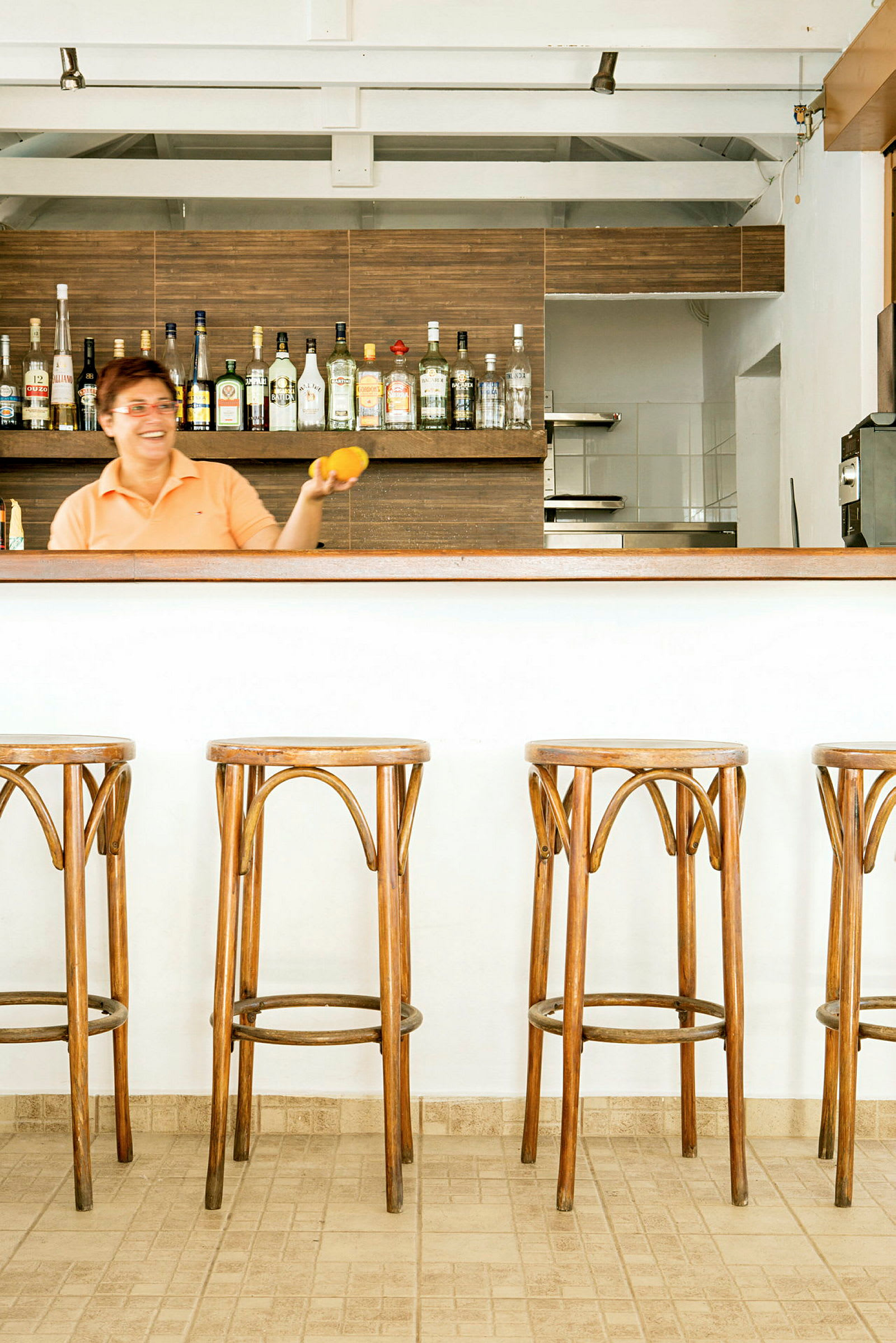 Fyra trästolar framför en bar med flaskor på hyllan. (AI-genererad text)