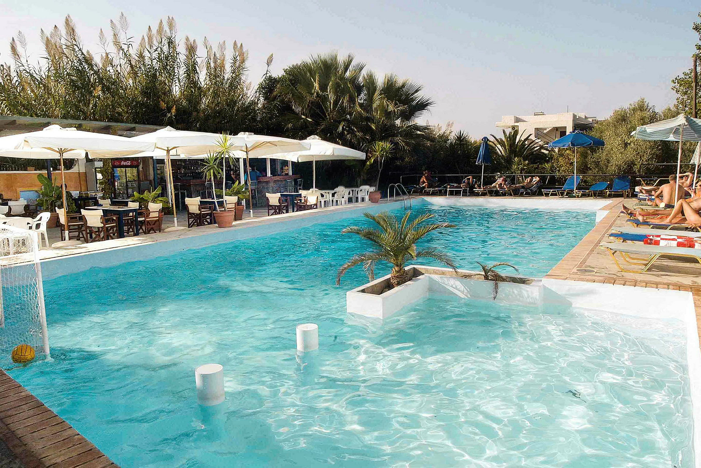 En swimmingpool med solstolar, parasoller och en serveringsyta i bakgrunden. (AI-genererad text)