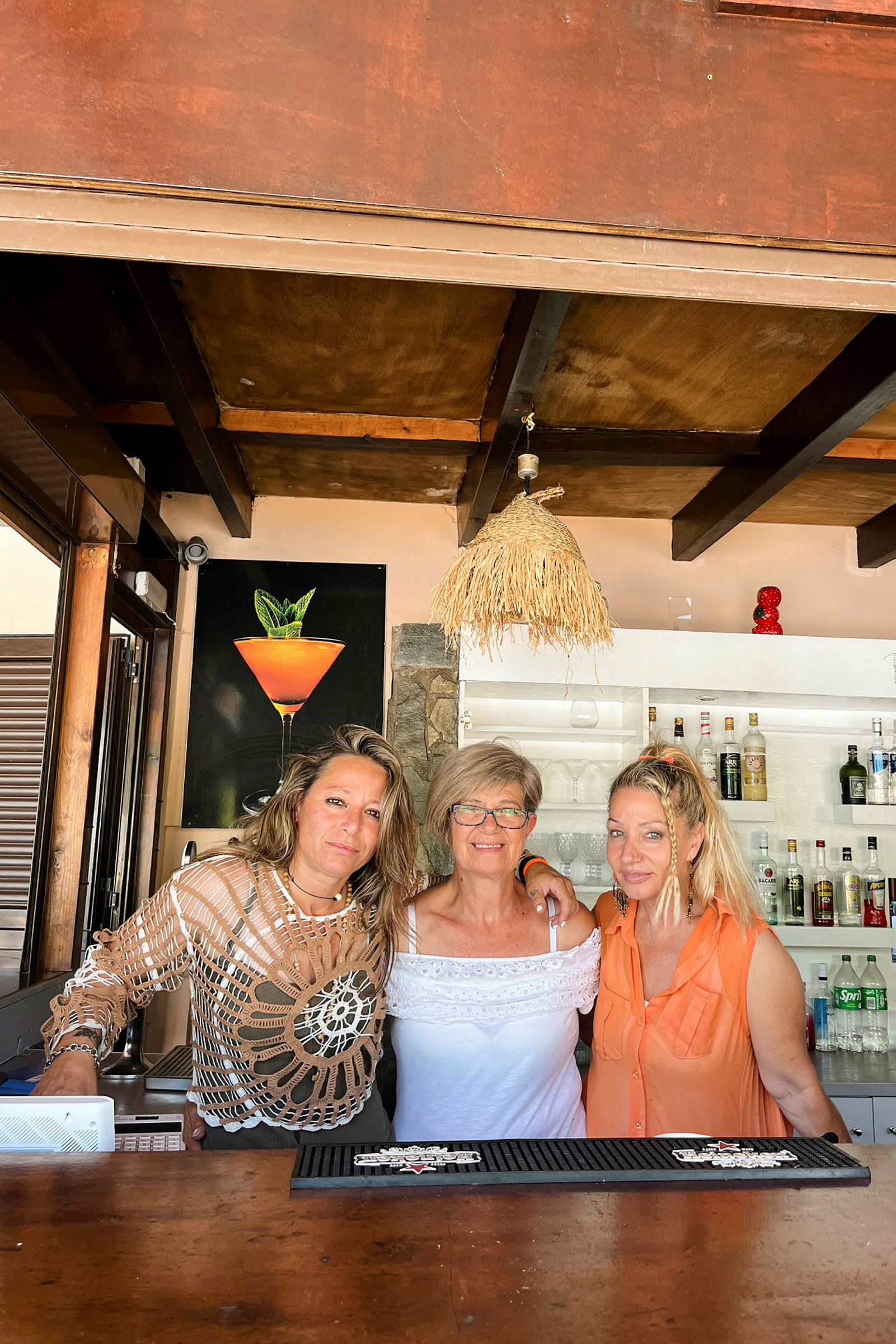 Tre kvinnor poserar vid en bar inomhus. (AI-genererad text)